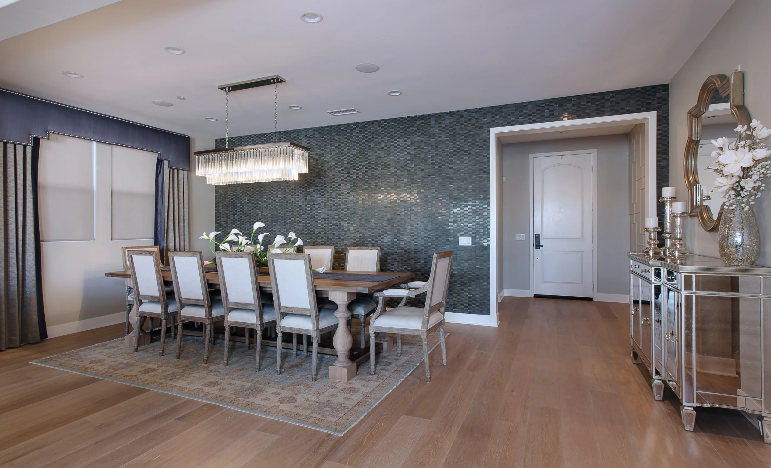 Dining room with textured blue wall, white chairs, and long pendant light
