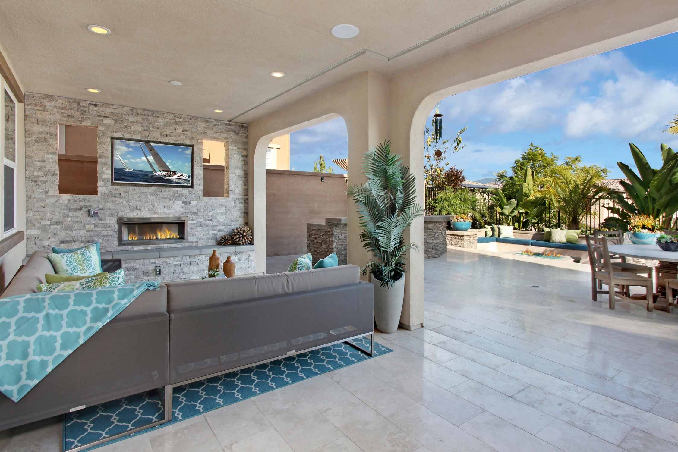 Covered outdoor living area with fireplace, pool, and garden view
