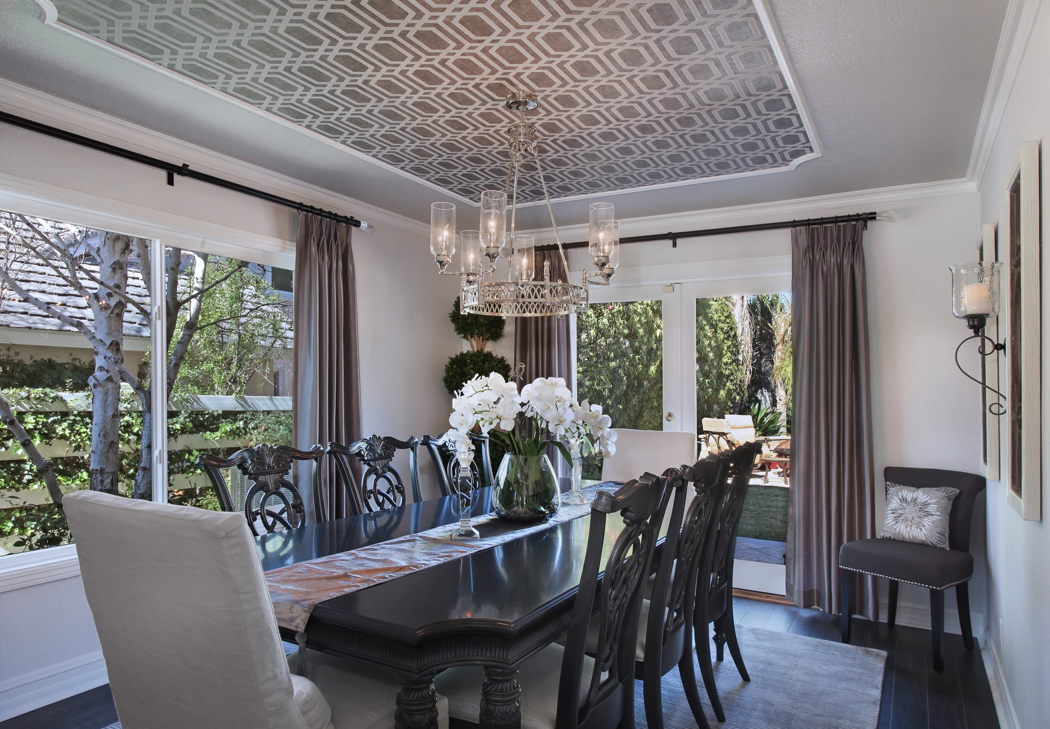 Dining room with dark wood table, patterned ceiling, and garden view