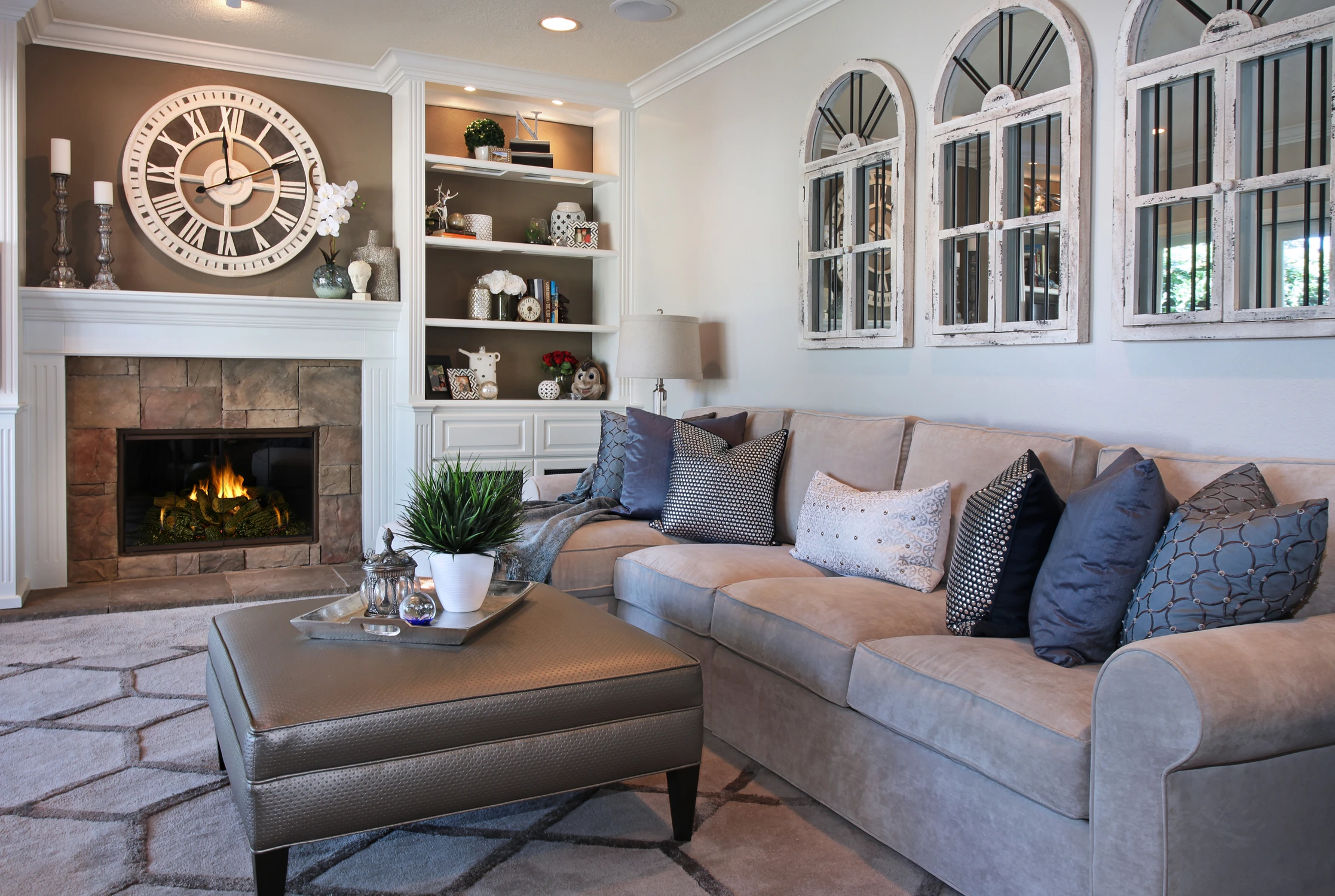 Family room fireplace with large clock, white cabinetry, and gray sectional