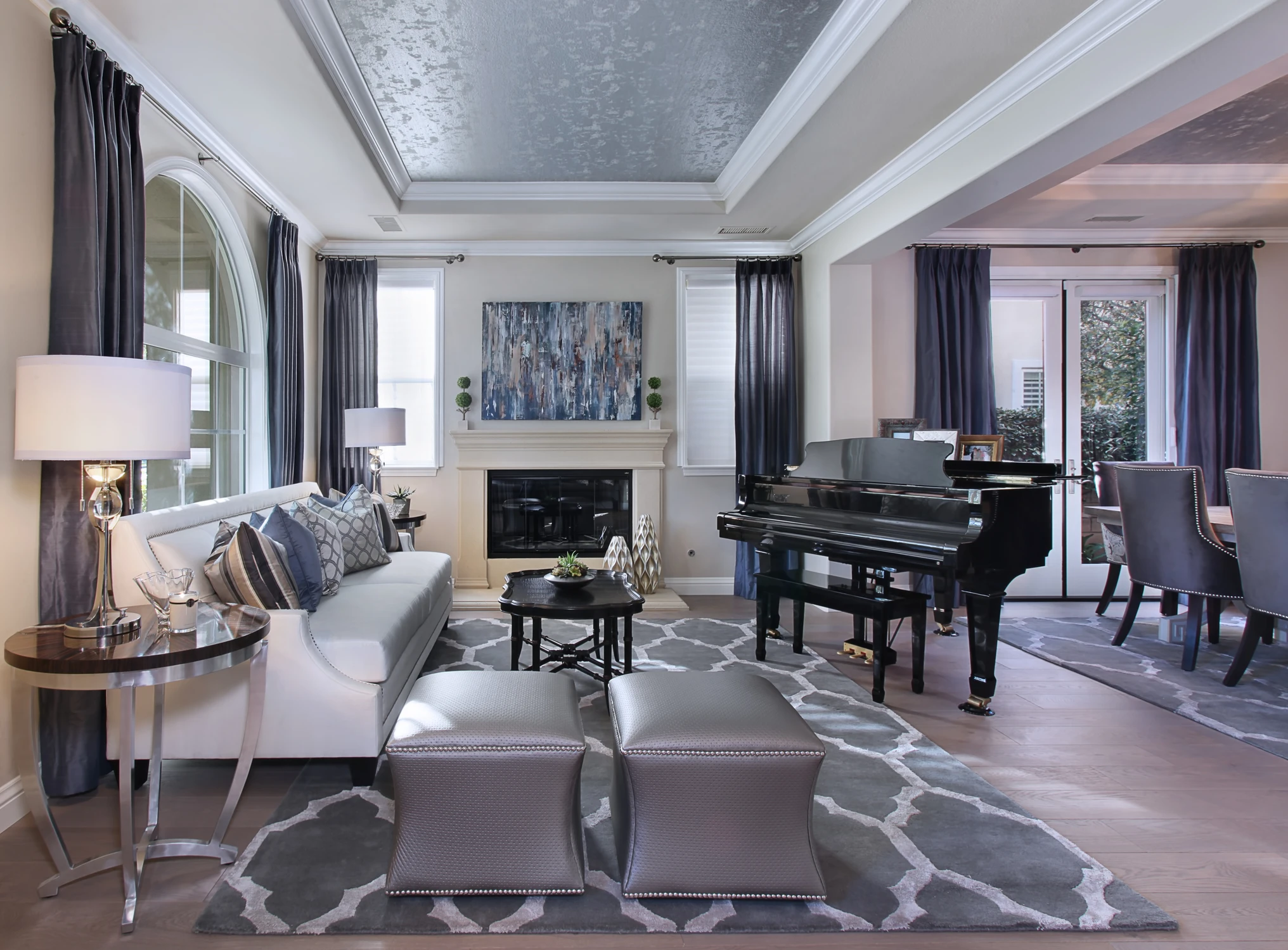 Formal living room with grand piano, dark drapery, and patterned rug