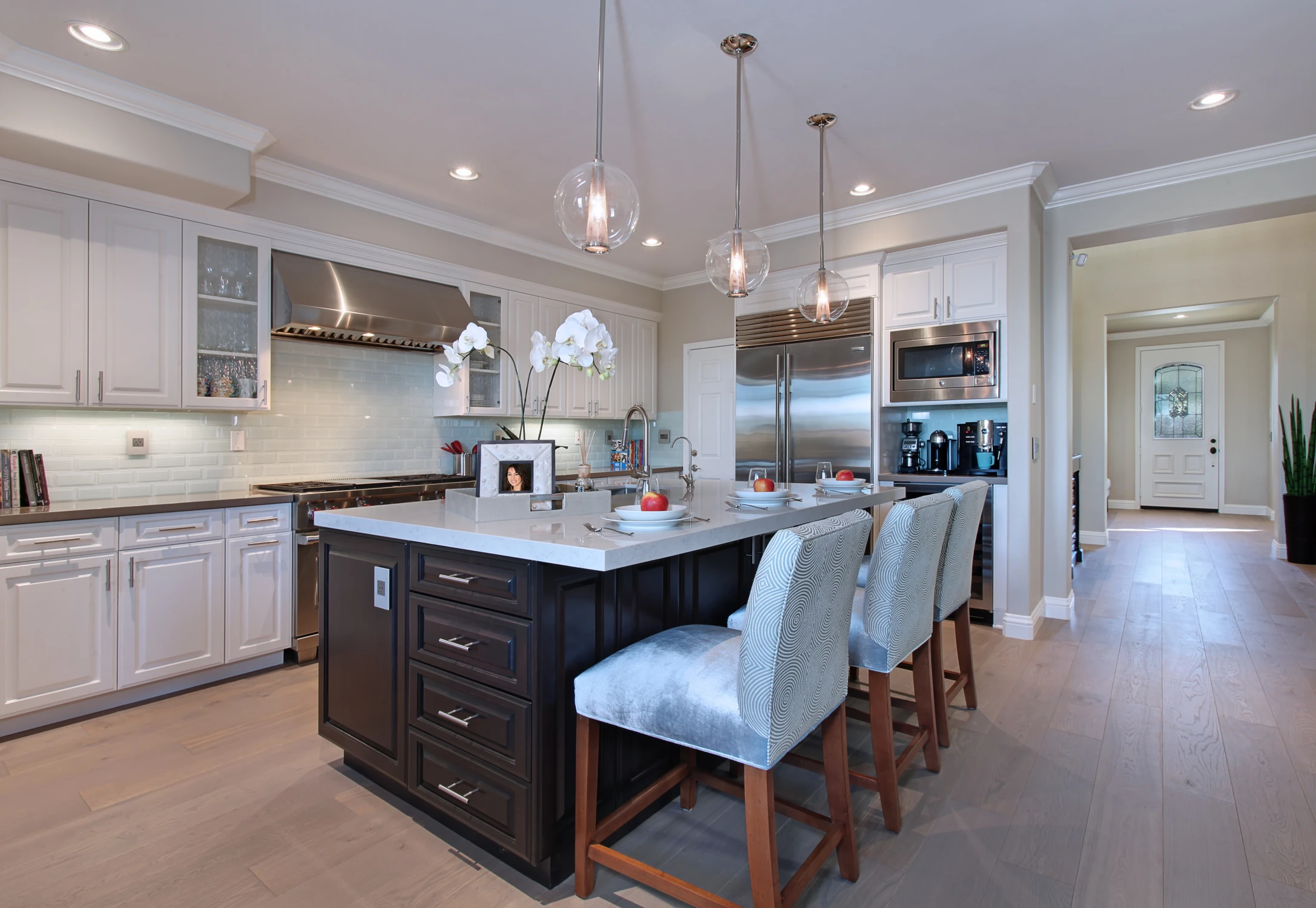 Kitchen with dark island, white cabinetry, and glass pendant lights