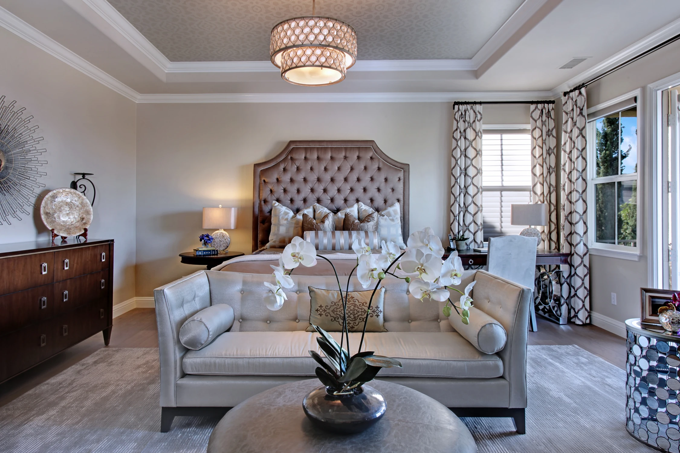 Bedroom with upholstered bed, layered pillows, and large patterned curtains