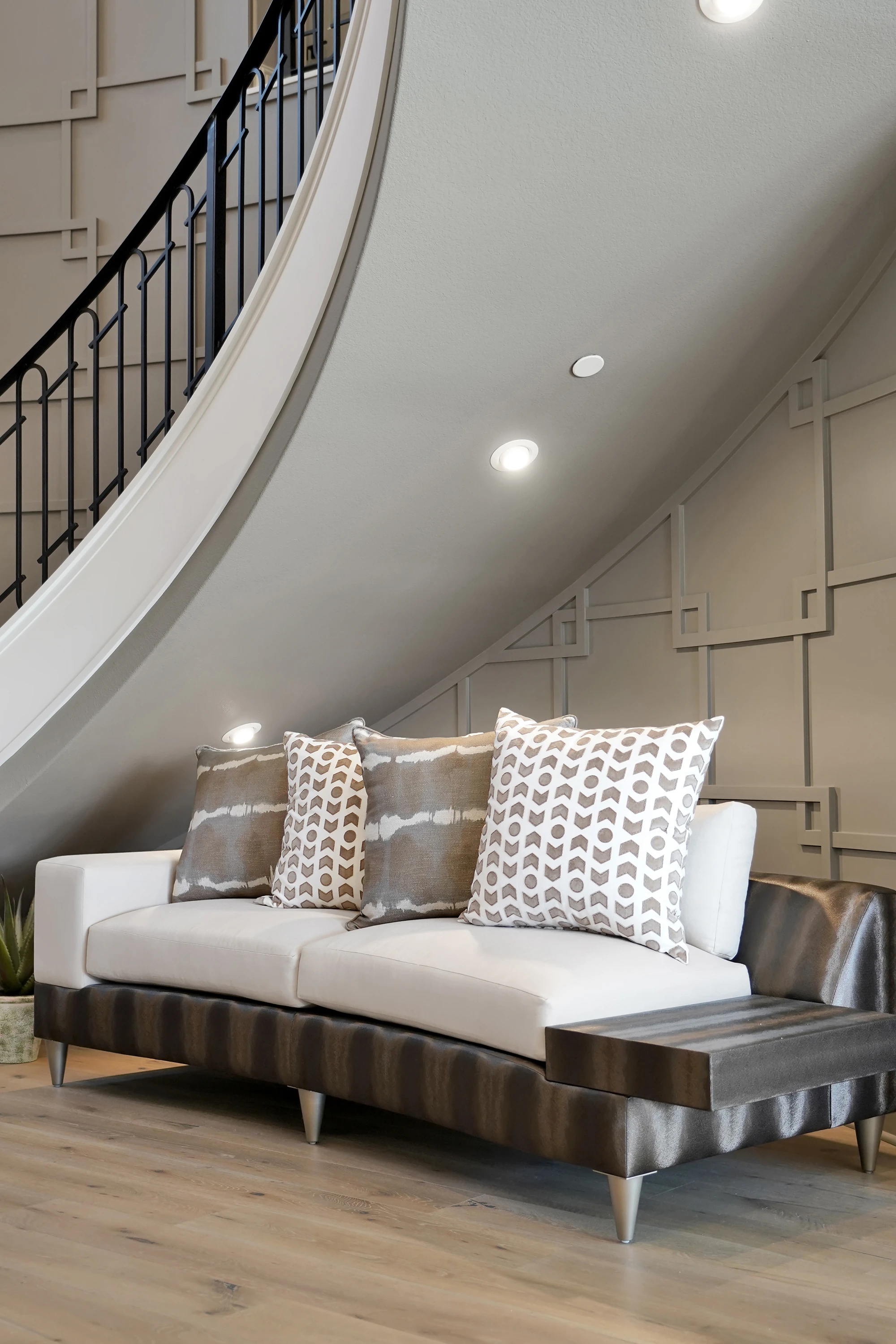 White upholstered bench beneath a curved staircase