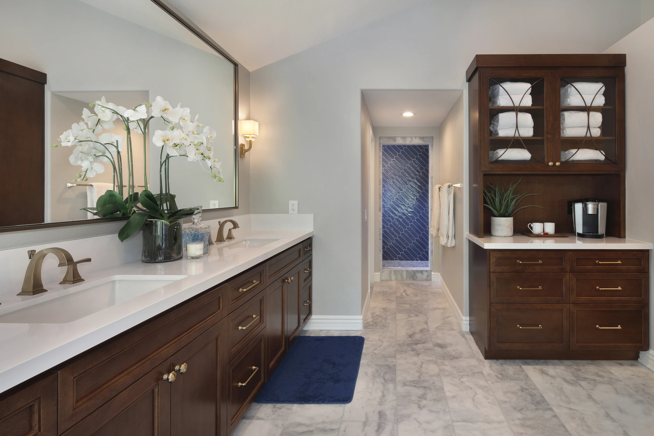 Long bathroom vanity with dark wood drawers, white counter, and framed mirror