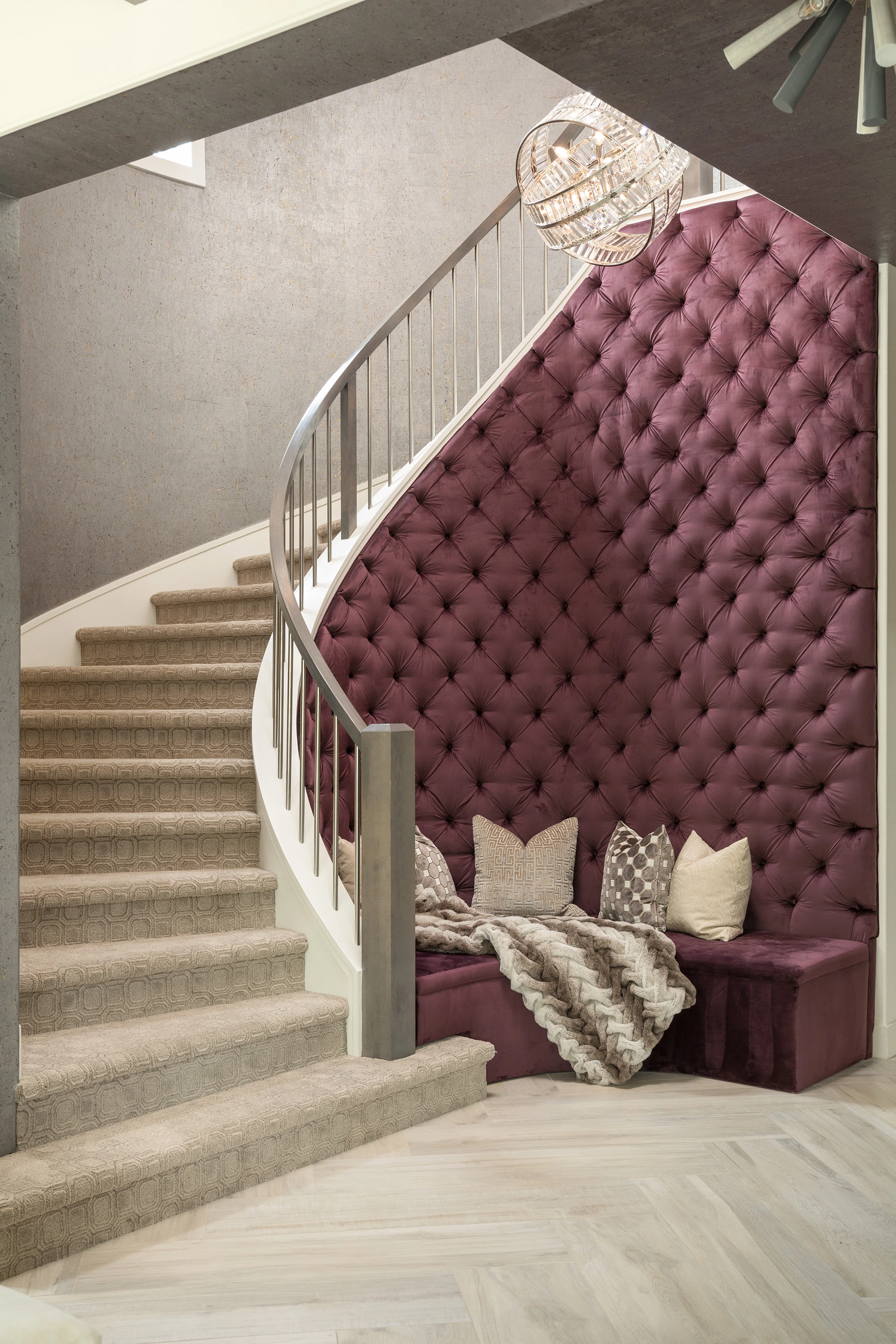 Plum tufted entryway bench beneath a curved staircase