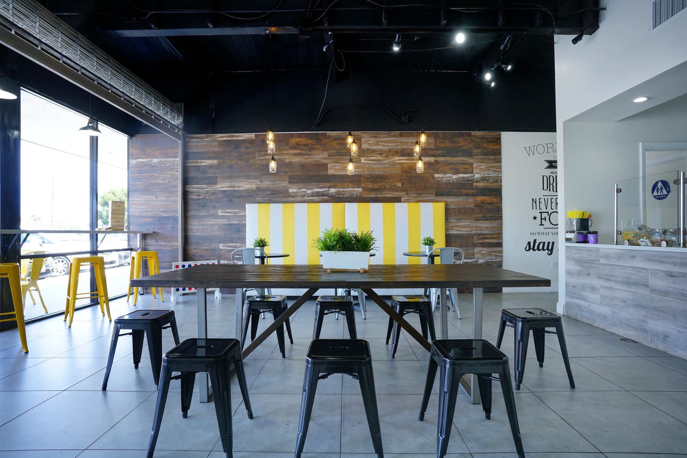 Food retail seating area with communal table, yellow booth, and wood wall