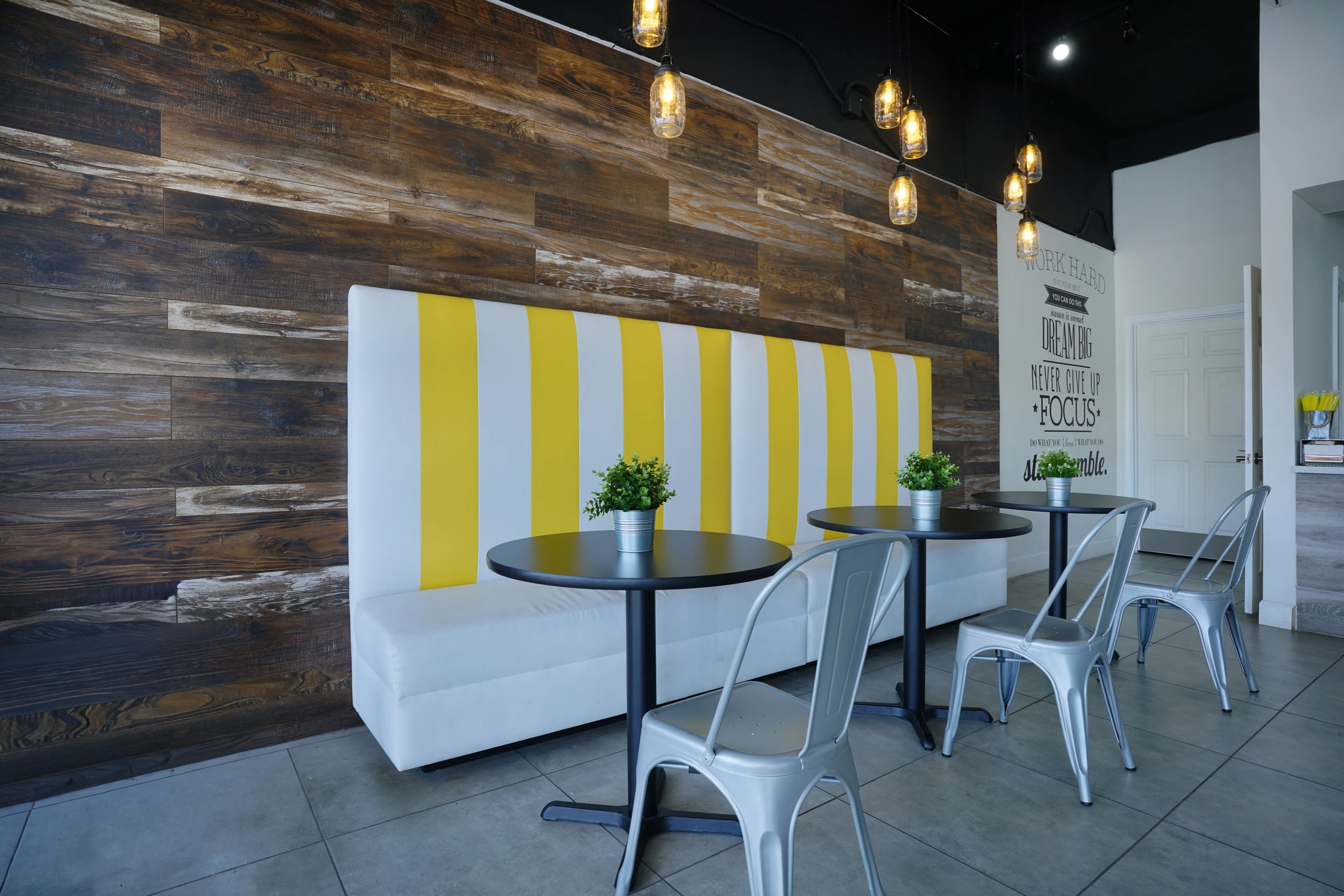 Yellow striped banquette beside reclaimed wood wall and pendant lights