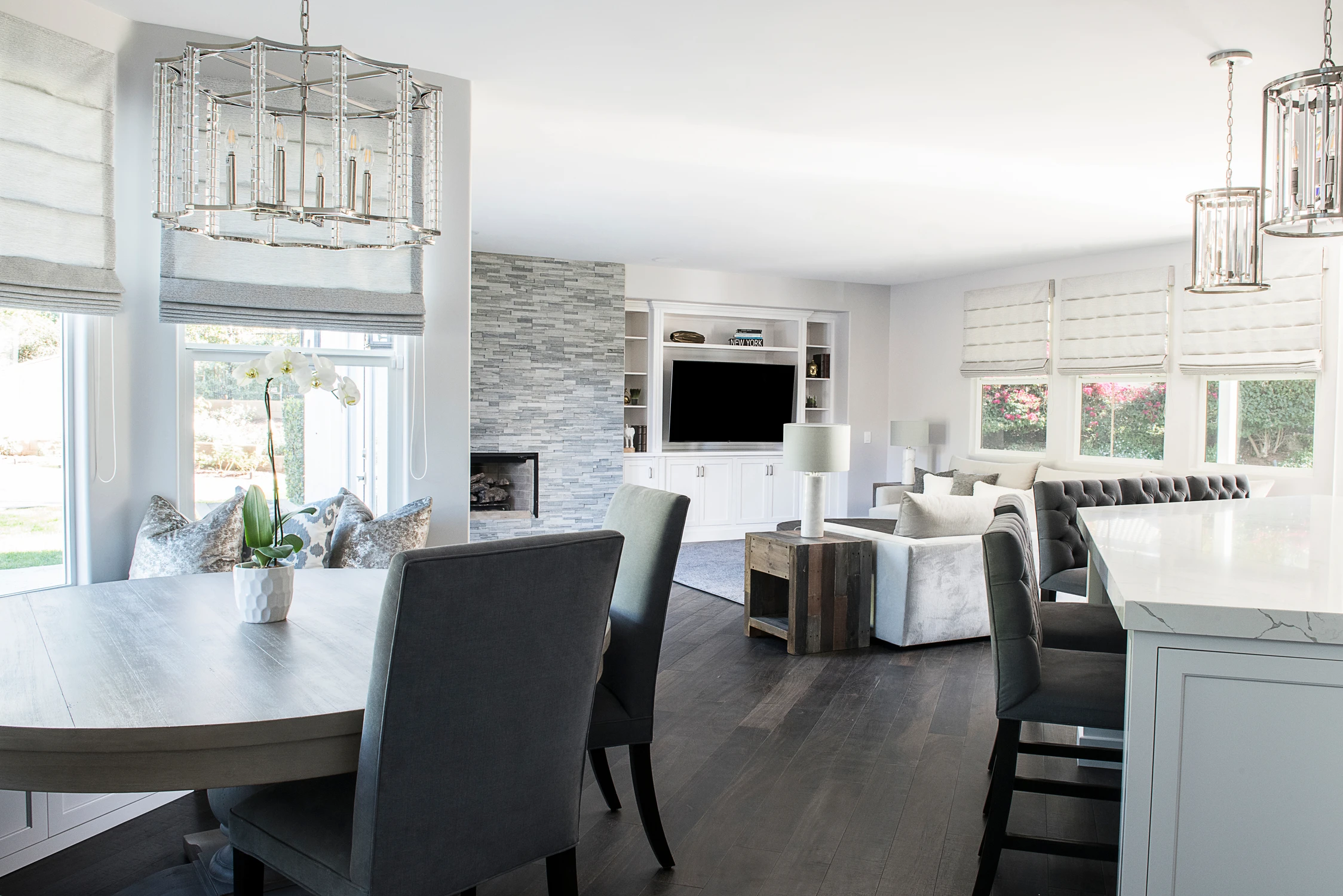 Open kitchen and dining area with gray stone fireplace and dark chairs