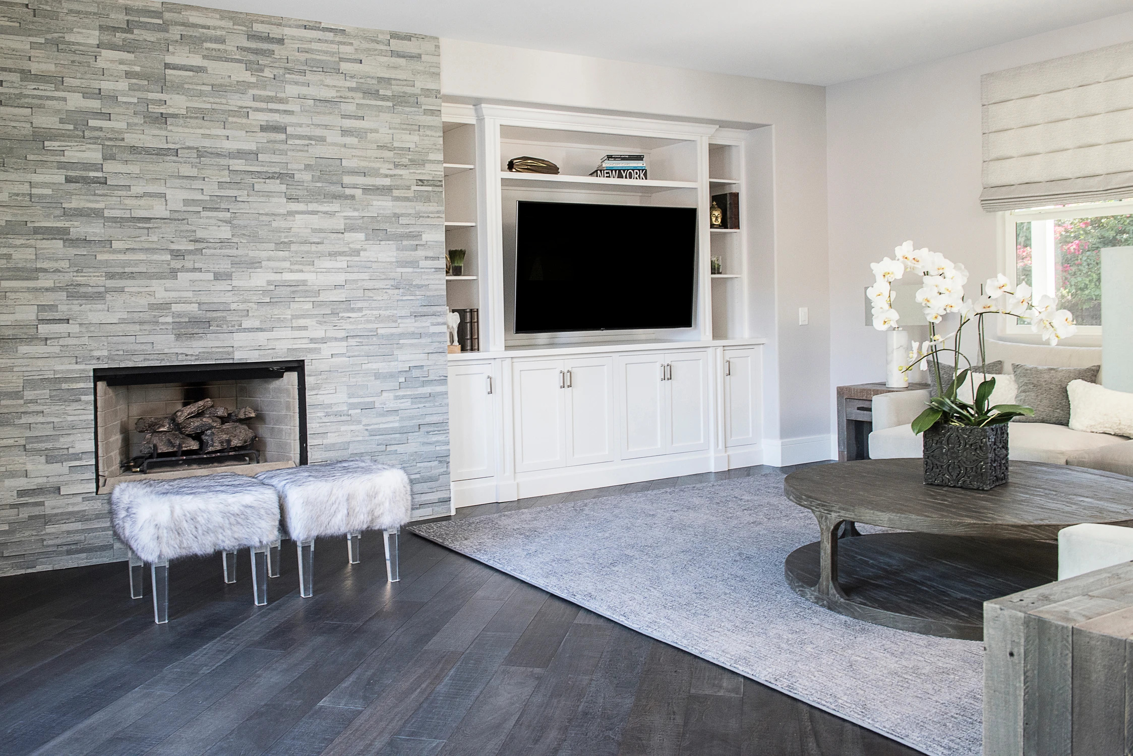 Family room with gray stone fireplace, white built-ins, and television