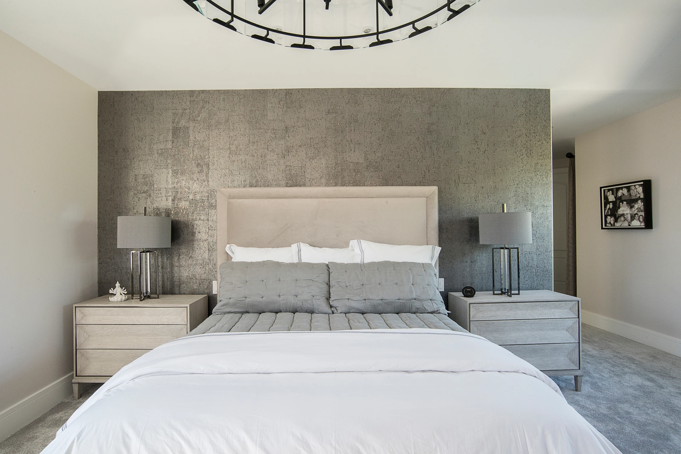 Primary bedroom with gray upholstered bed and silver textured accent wall