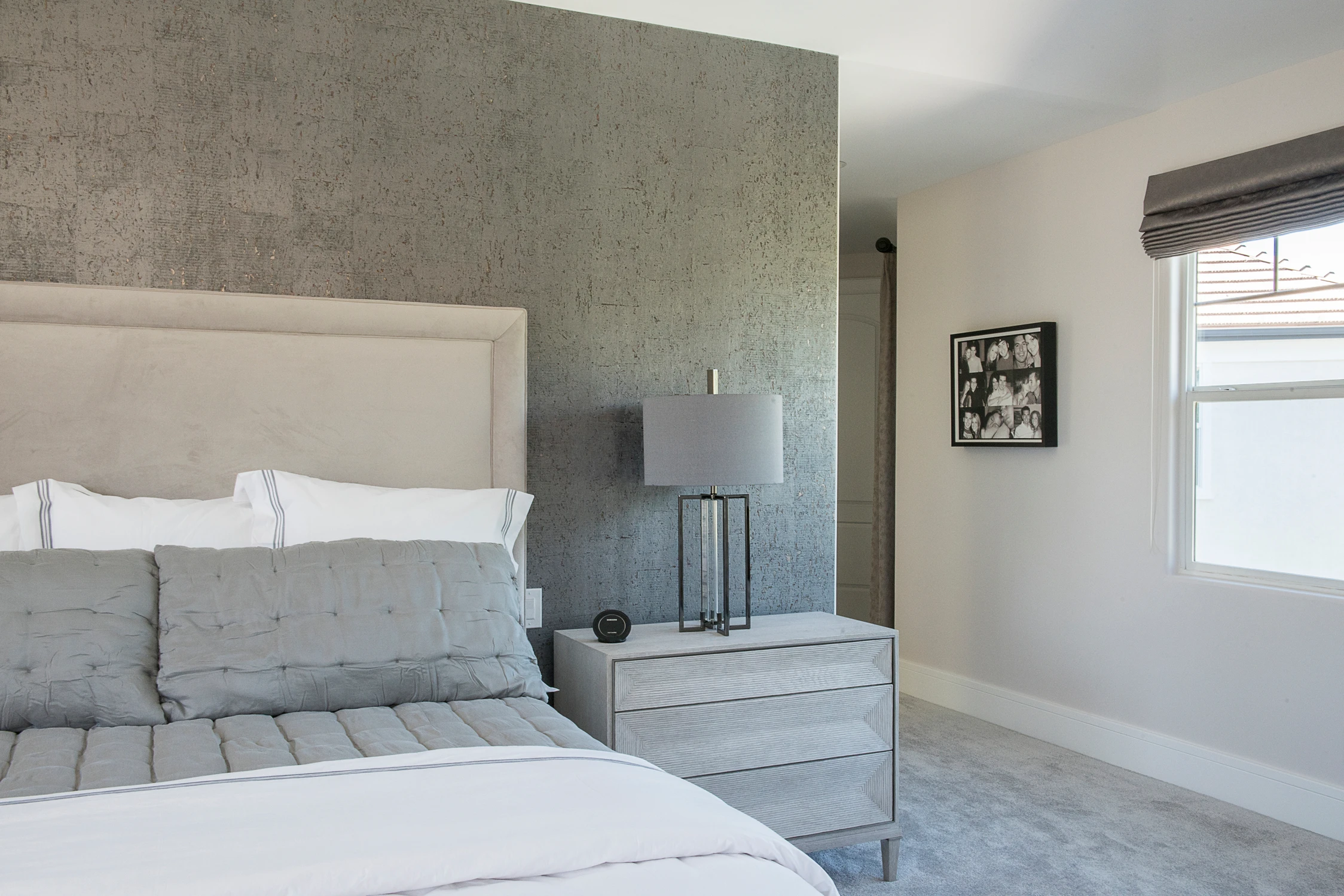 Primary bedroom with upholstered bed, gray dresser, and textured accent wall