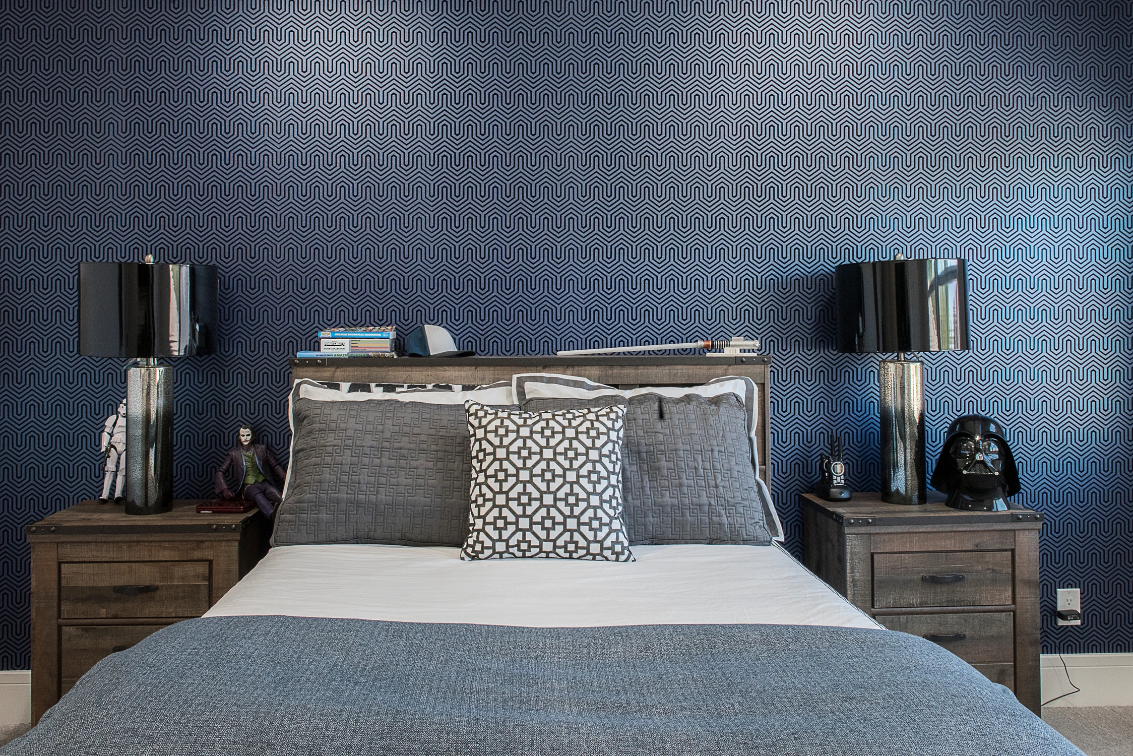 Kids' bedroom with wood bed, blue geometric wallpaper, and dark lamps