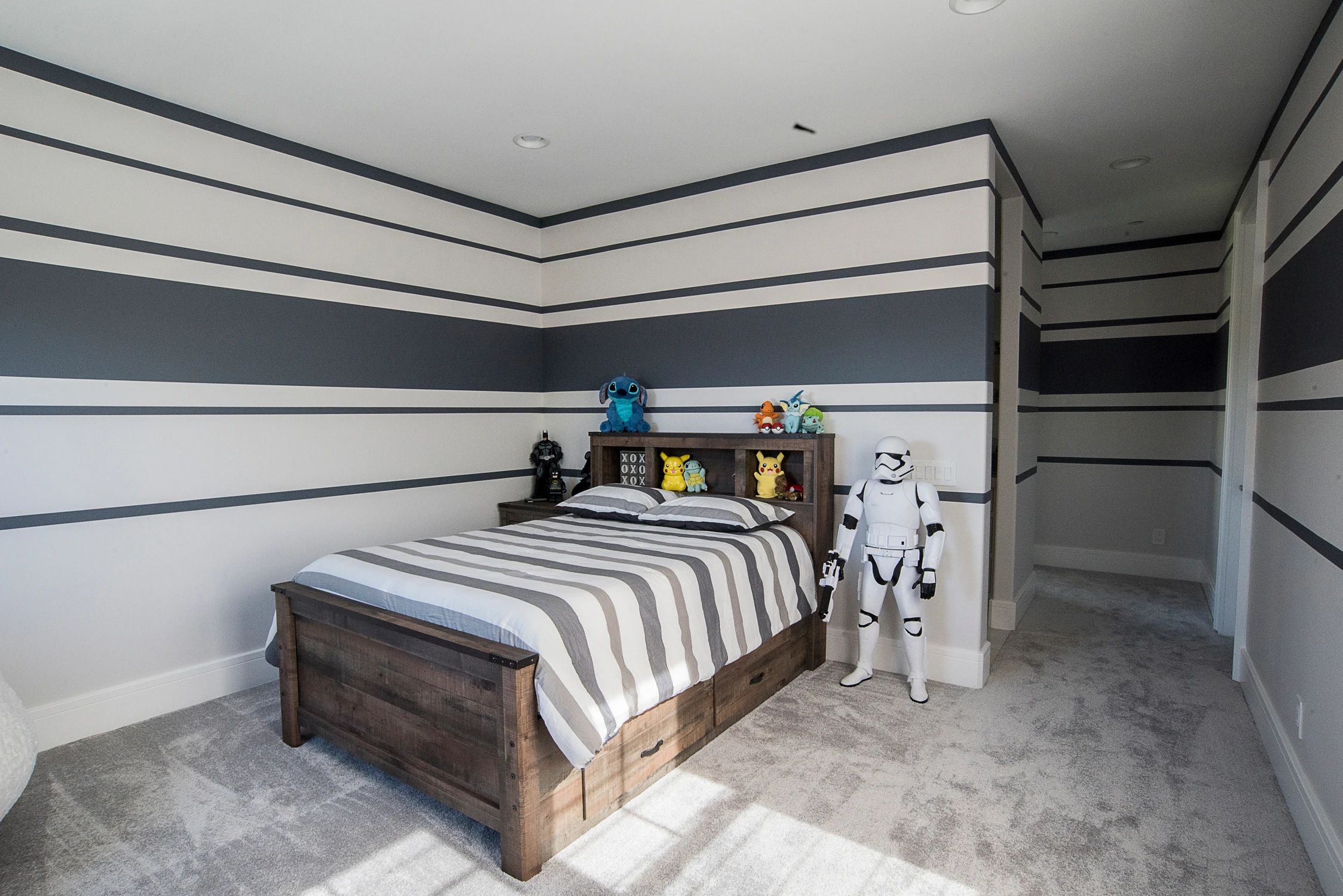 Kids' bedroom with striped walls, wood bed, and character toys