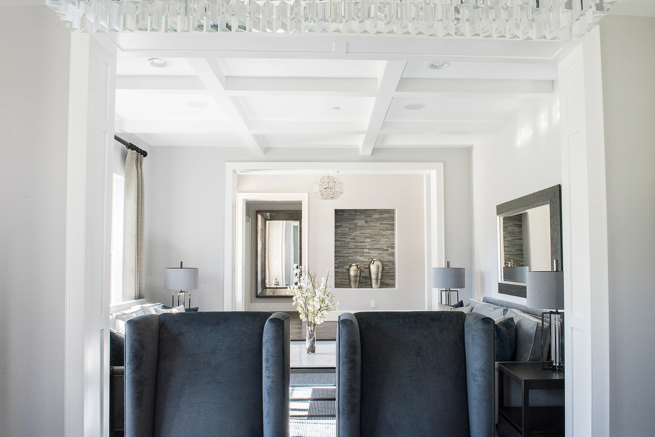 Formal living room with gray sofas, black chairs, and coffered ceiling