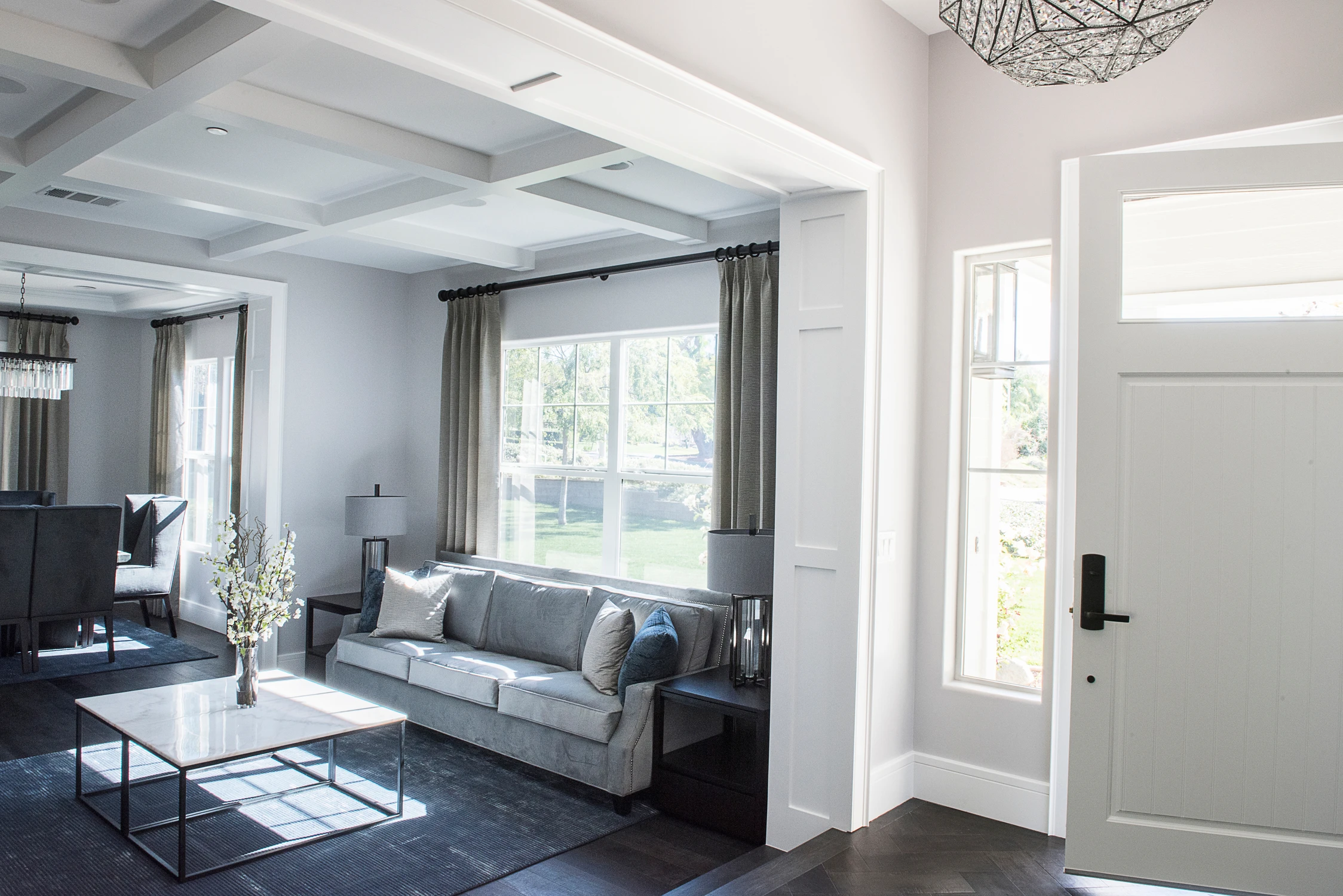 Gray sofa beneath coffered ceiling beside entry hall