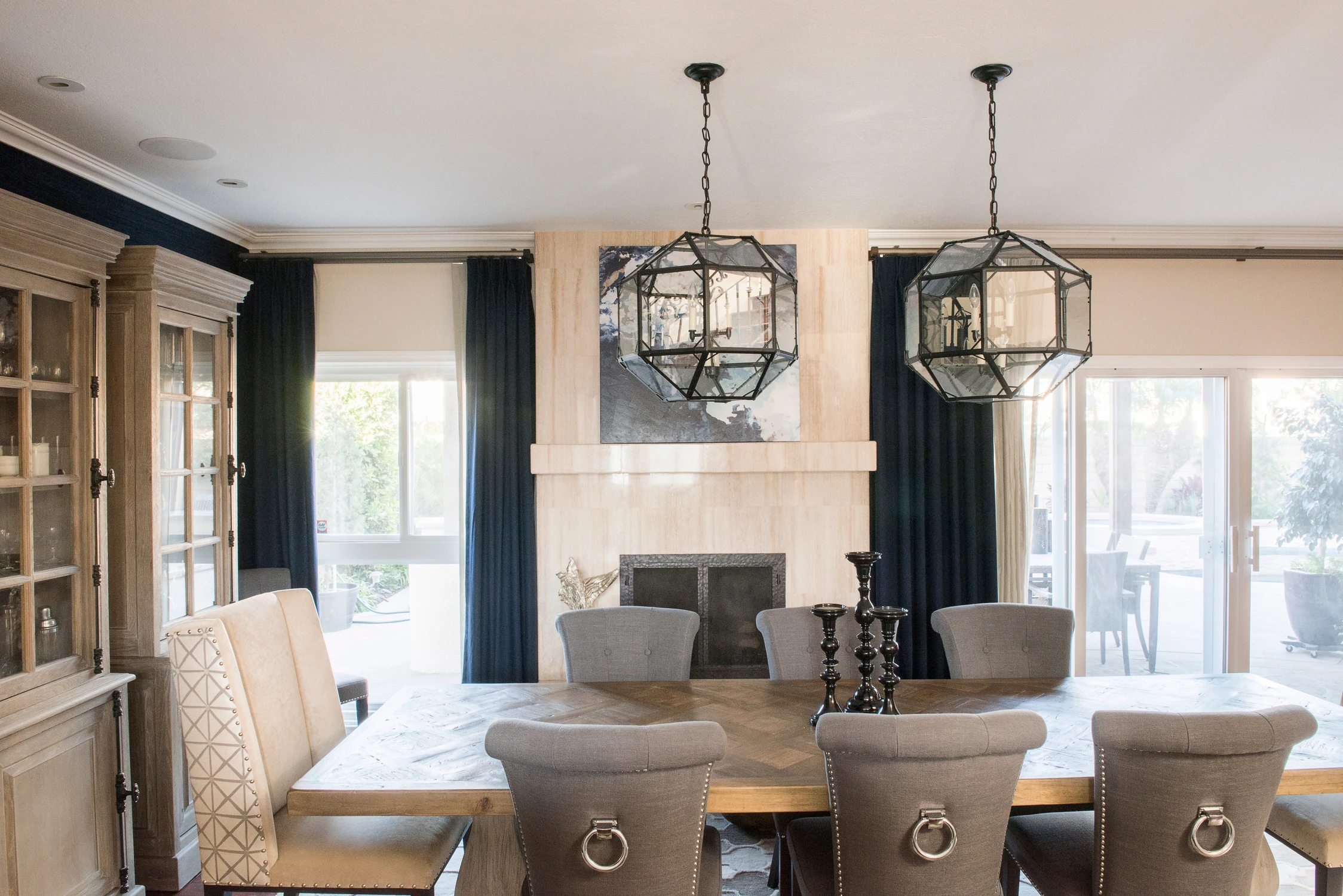 Gray upholstered dining chairs beneath open metal pendant lights