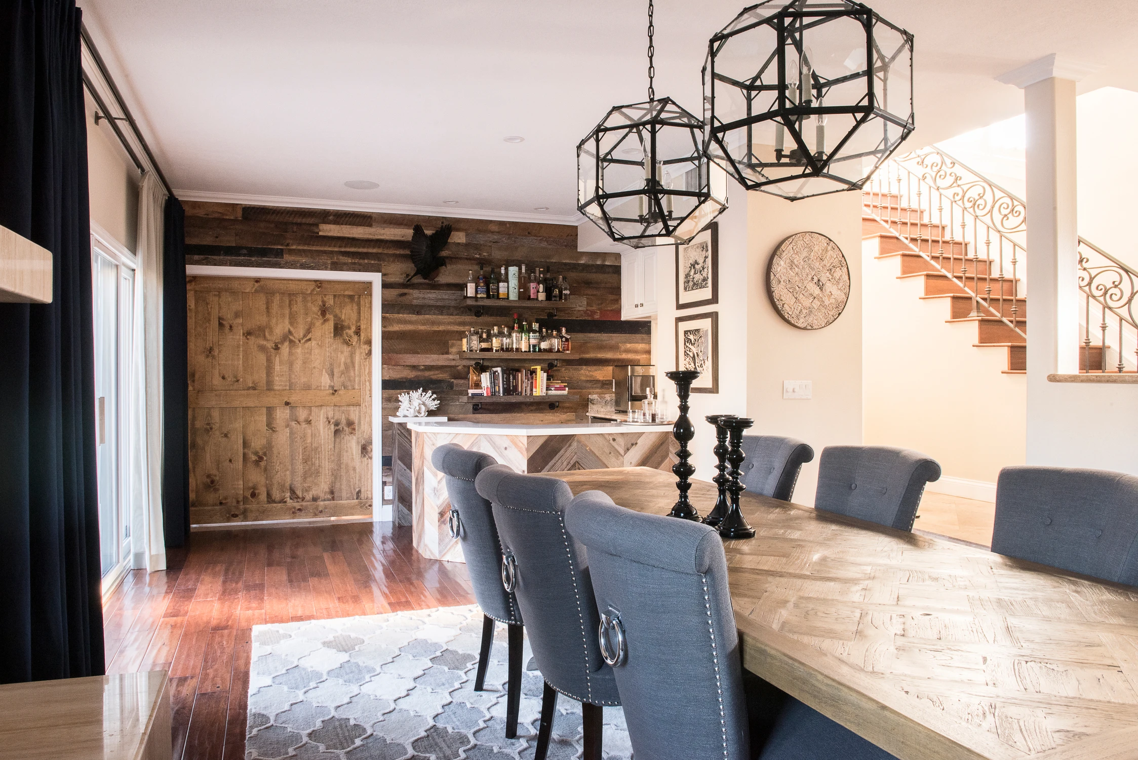 Dining table beside reclaimed wood feature wall and staircase