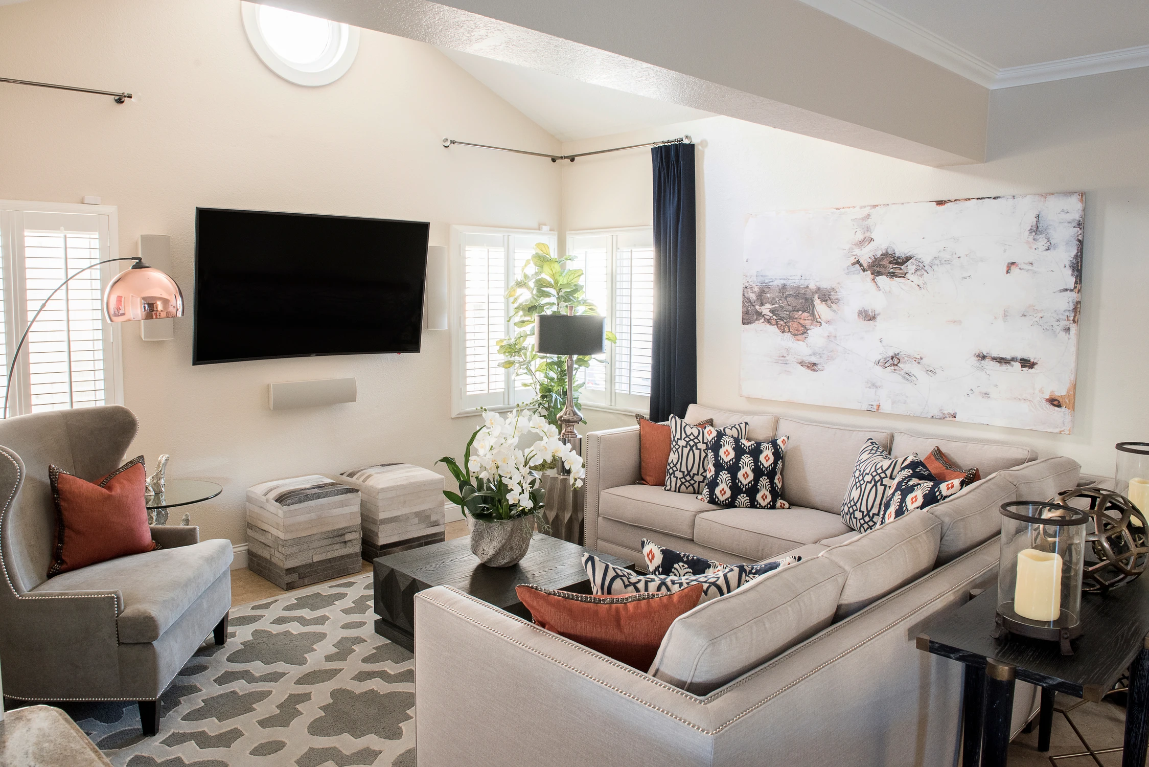 Light-filled living room with a wall-mounted television and patterned chairs