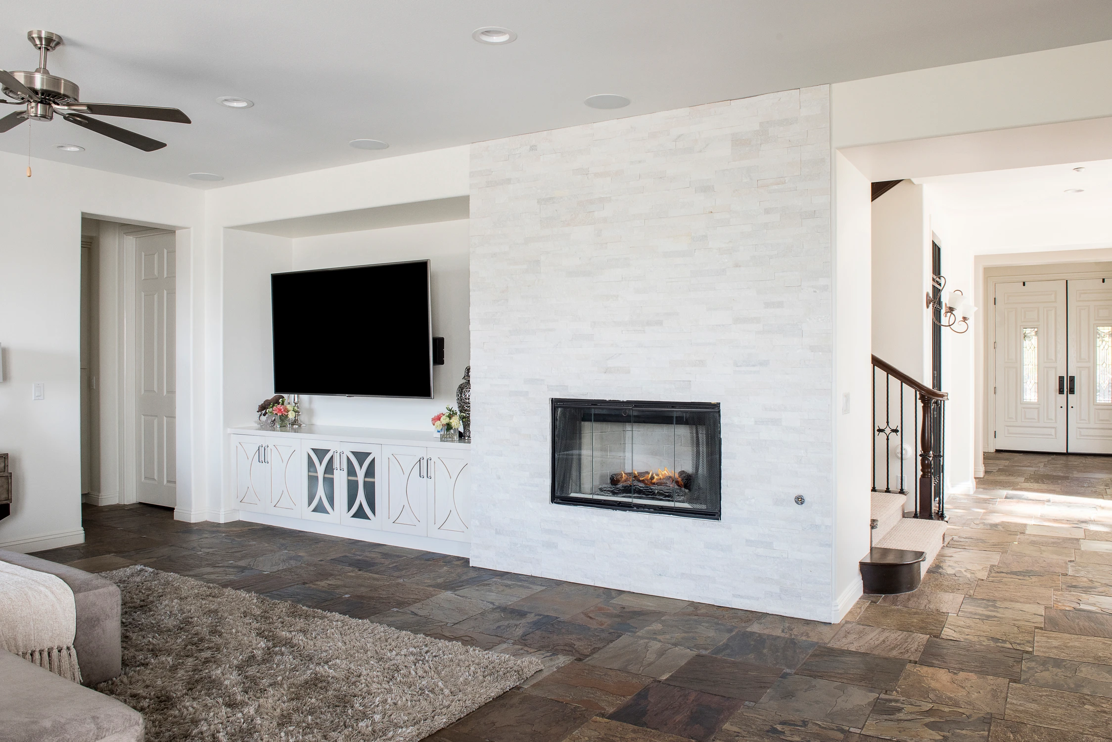 Living room with white stone fireplace wall and wall-mounted television