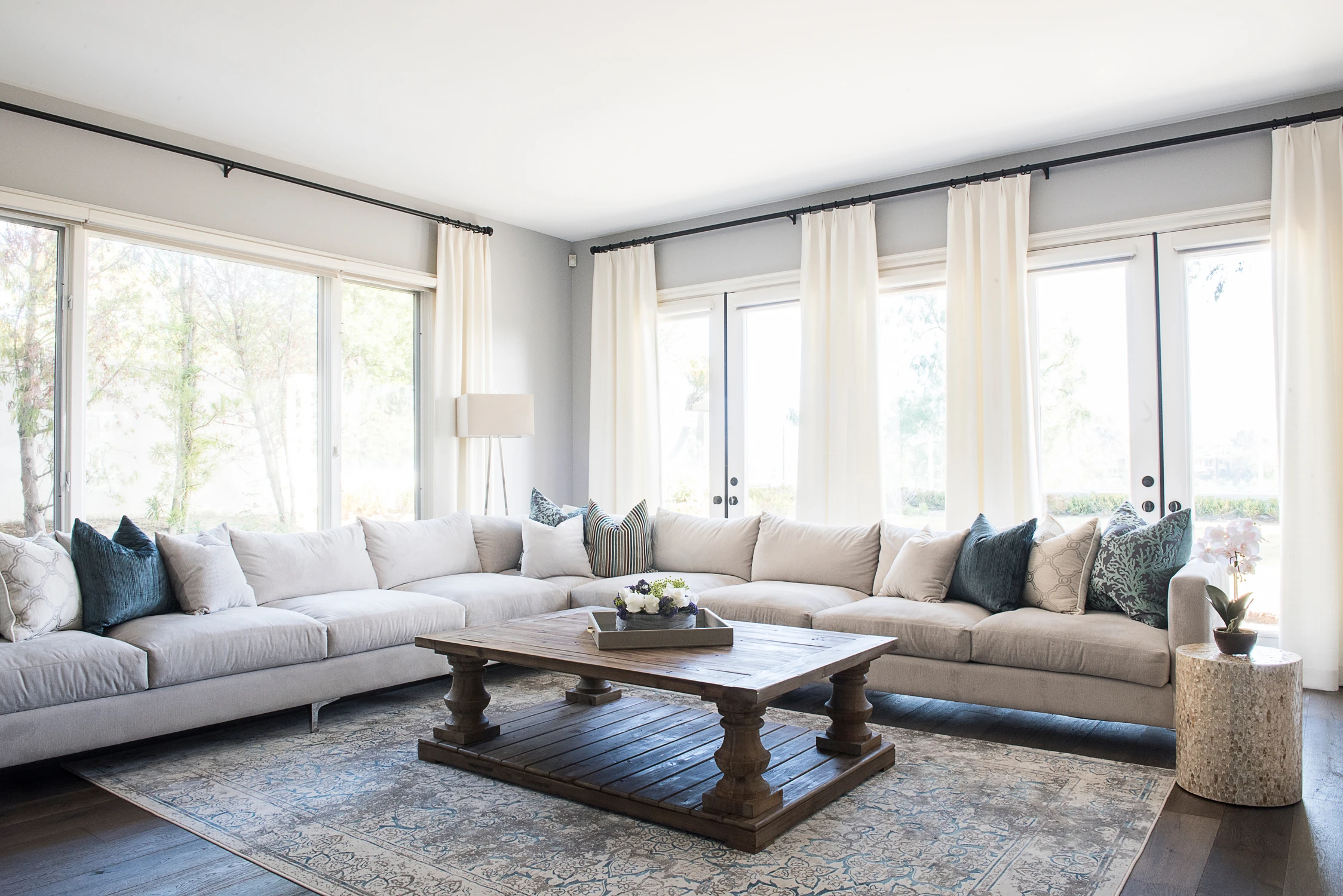 Living room with long sectional, wood coffee table, and bay windows