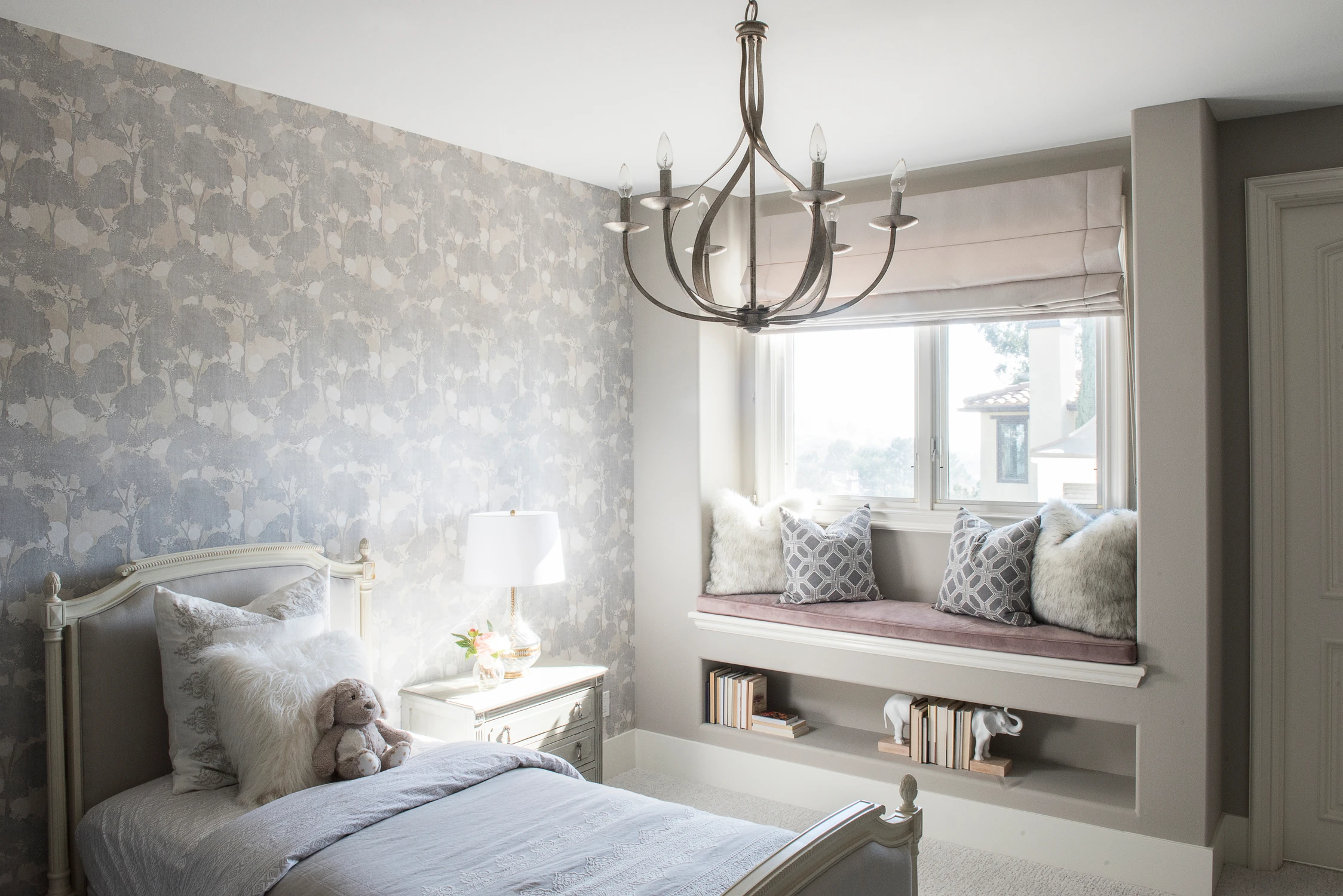 Bedroom with cushioned window bench and pale wood nightstand