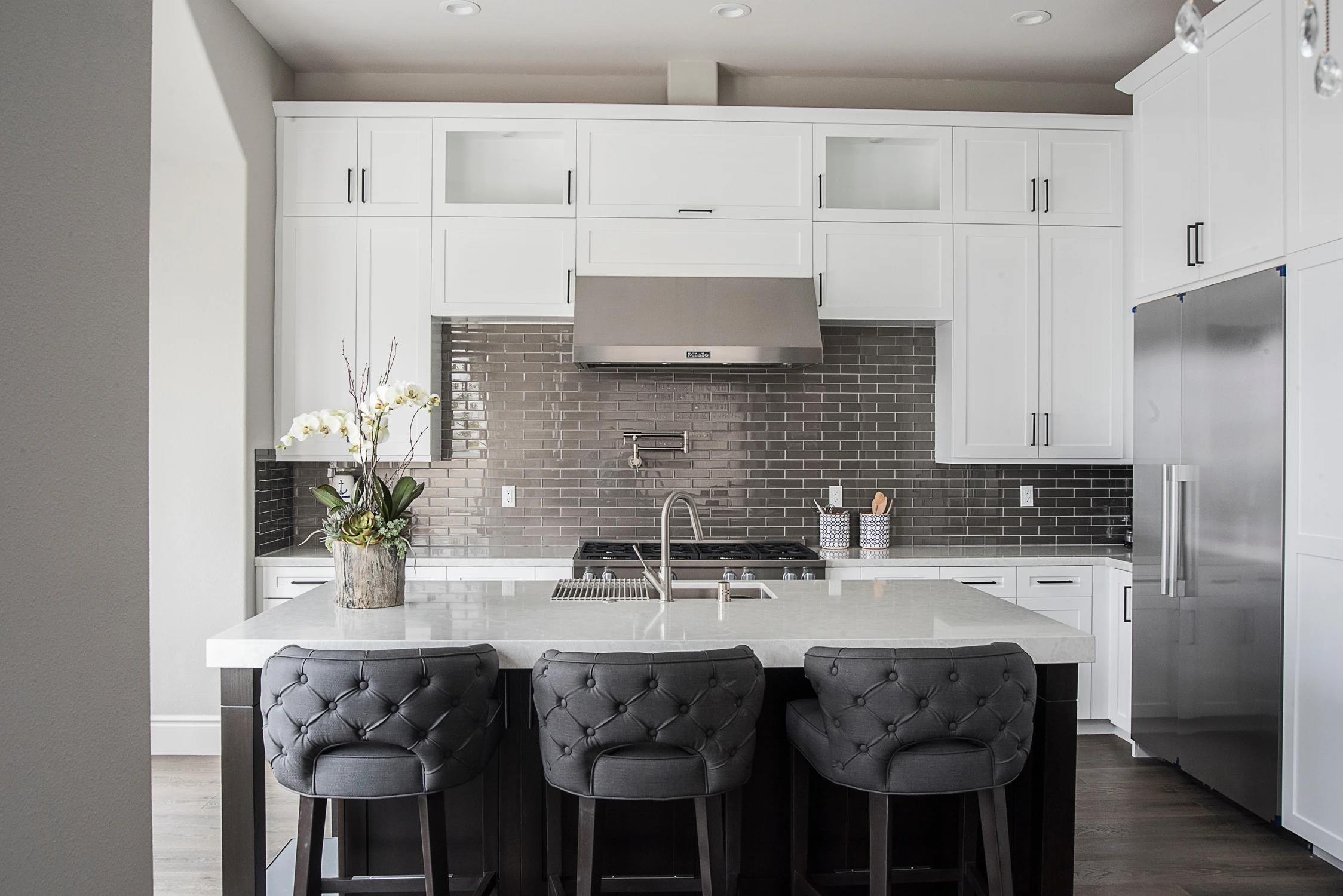 White kitchen with black island and gray backsplash