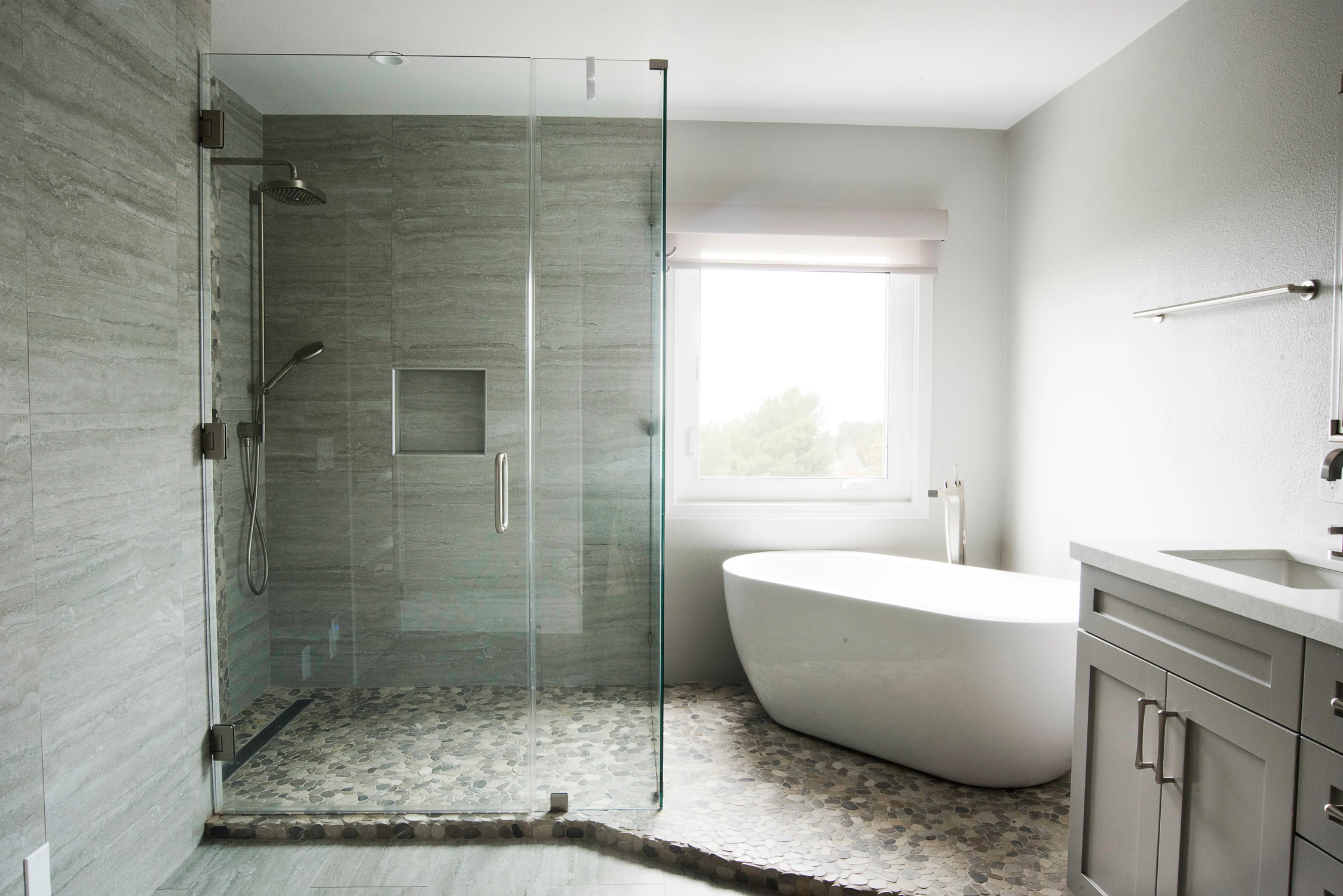 Bathroom with glass shower, freestanding tub, and gray vanity
