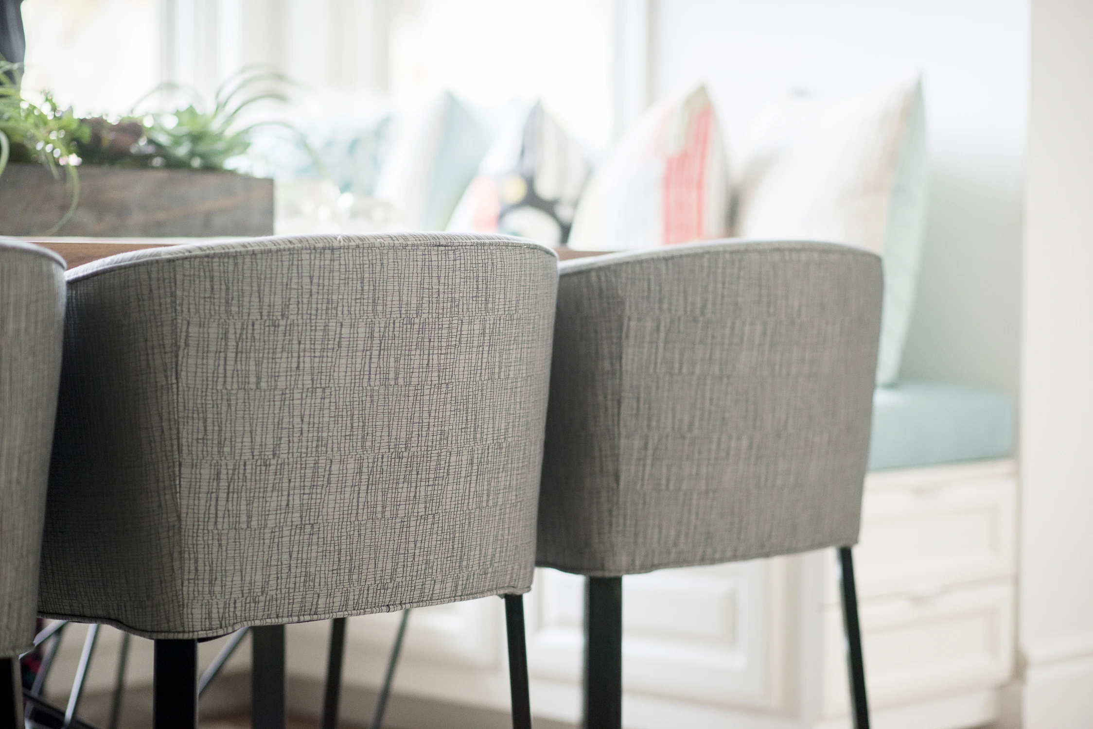 Dark dining chair backs beside a pale wood dining table