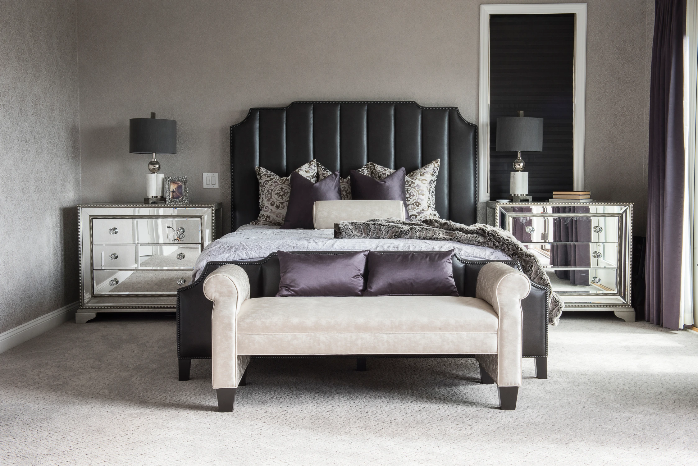 Bedroom with tall black upholstered headboard and pale bench
