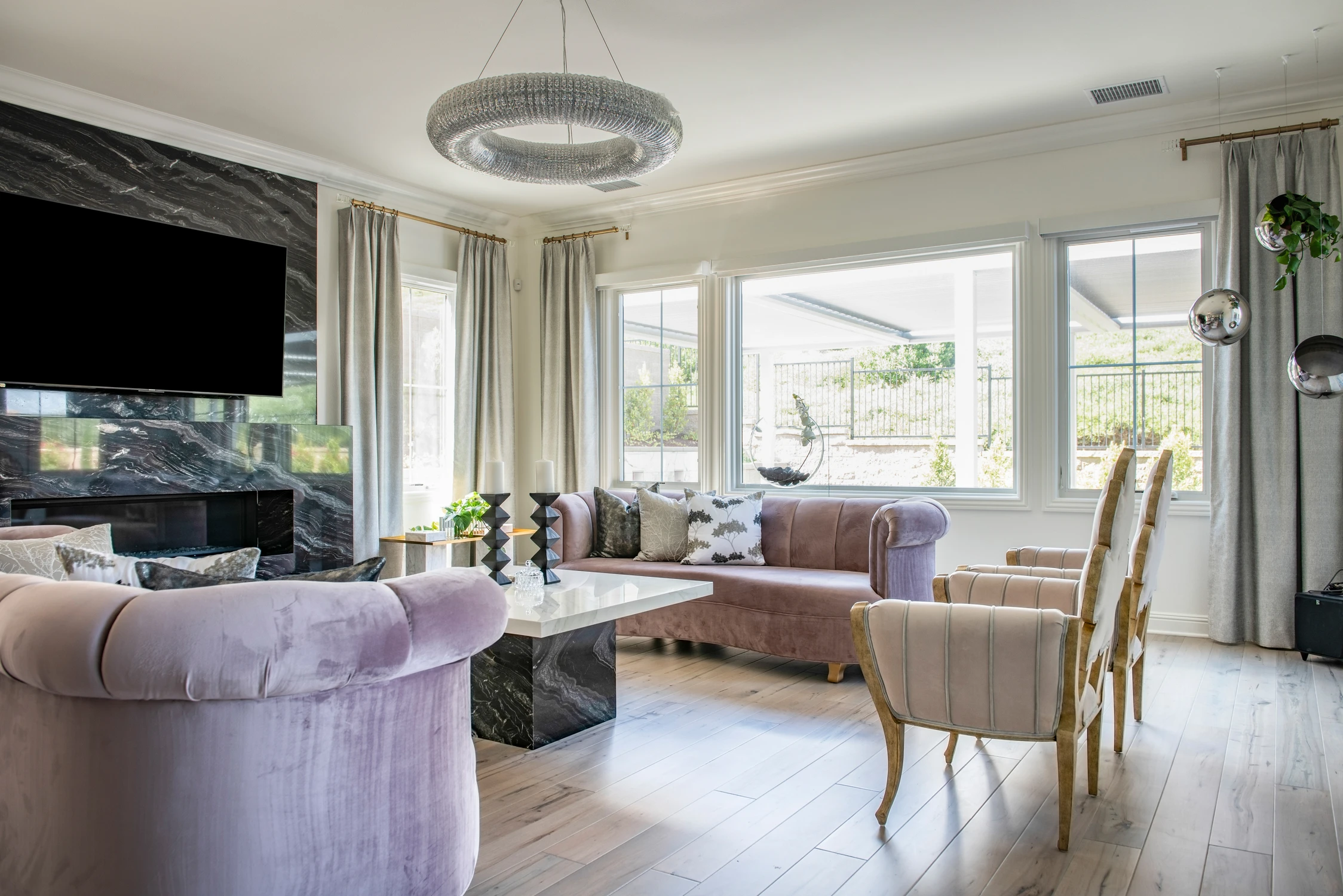 Living room with blush seating, black marble fireplace, and large windows