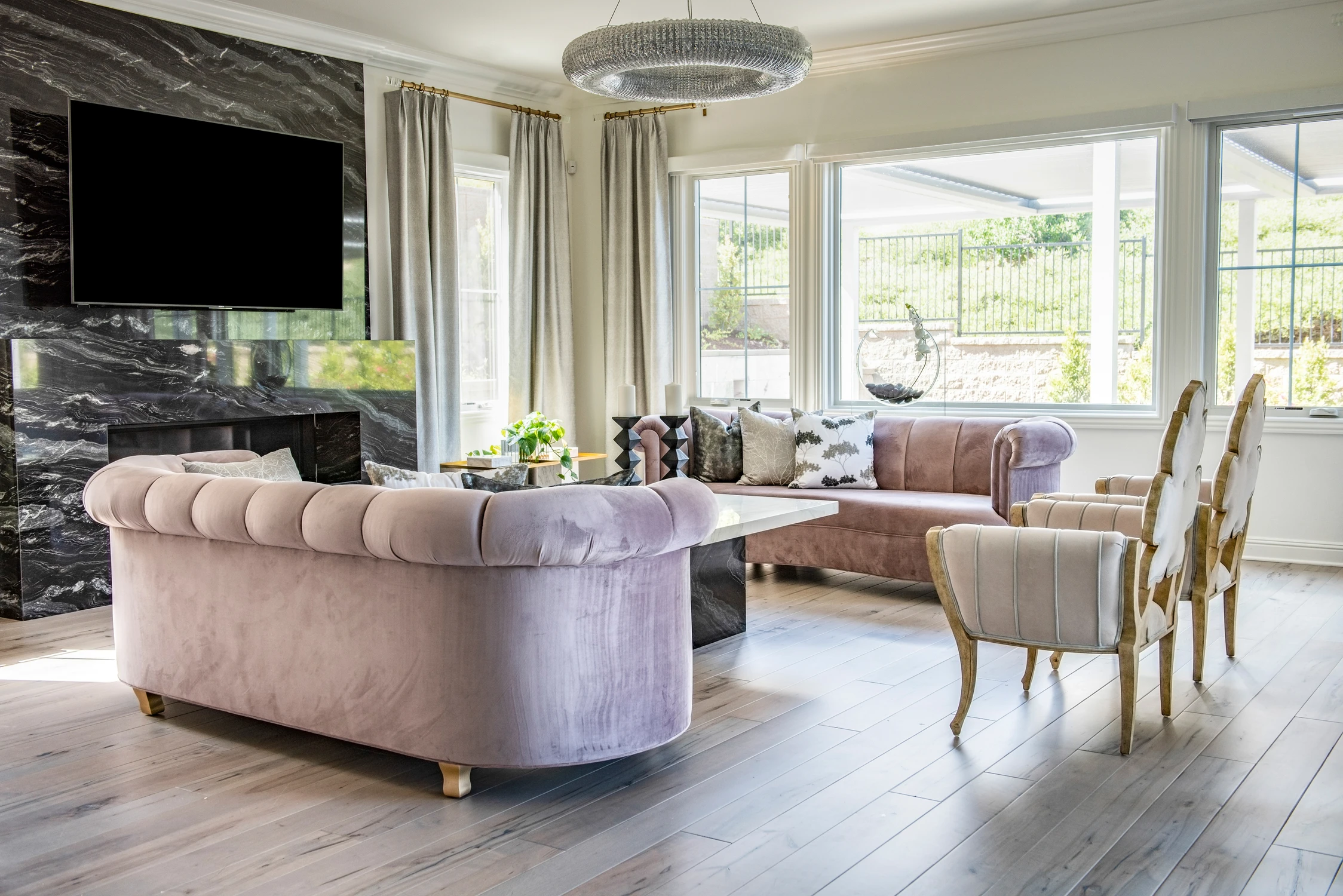 Blush sofas and white coffee table beside black marble fireplace
