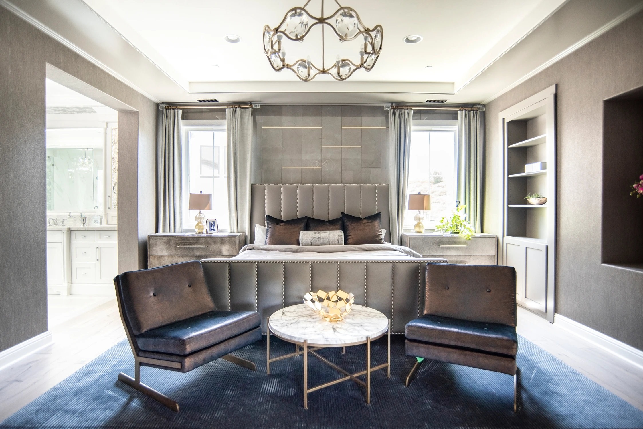 Bedroom with upholstered bed, leather chairs, and marble table