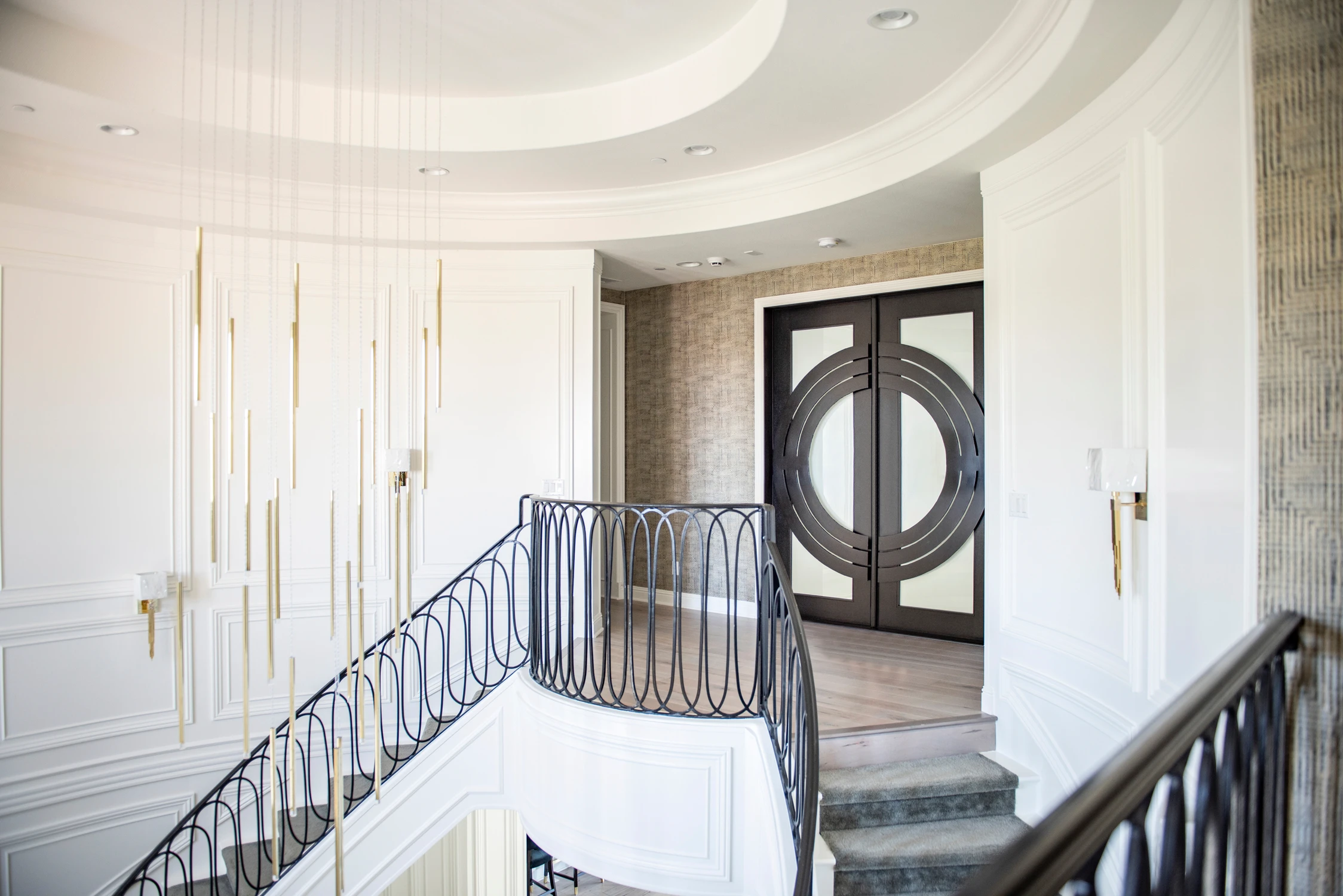 Upper foyer with black railings, pendant lights, and dark double doors