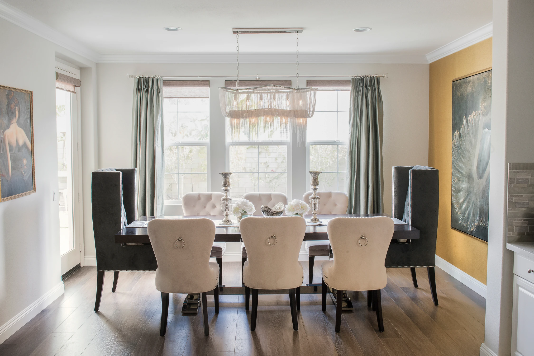Dining room with dark table, yellow accent wall, and crystal chandelier