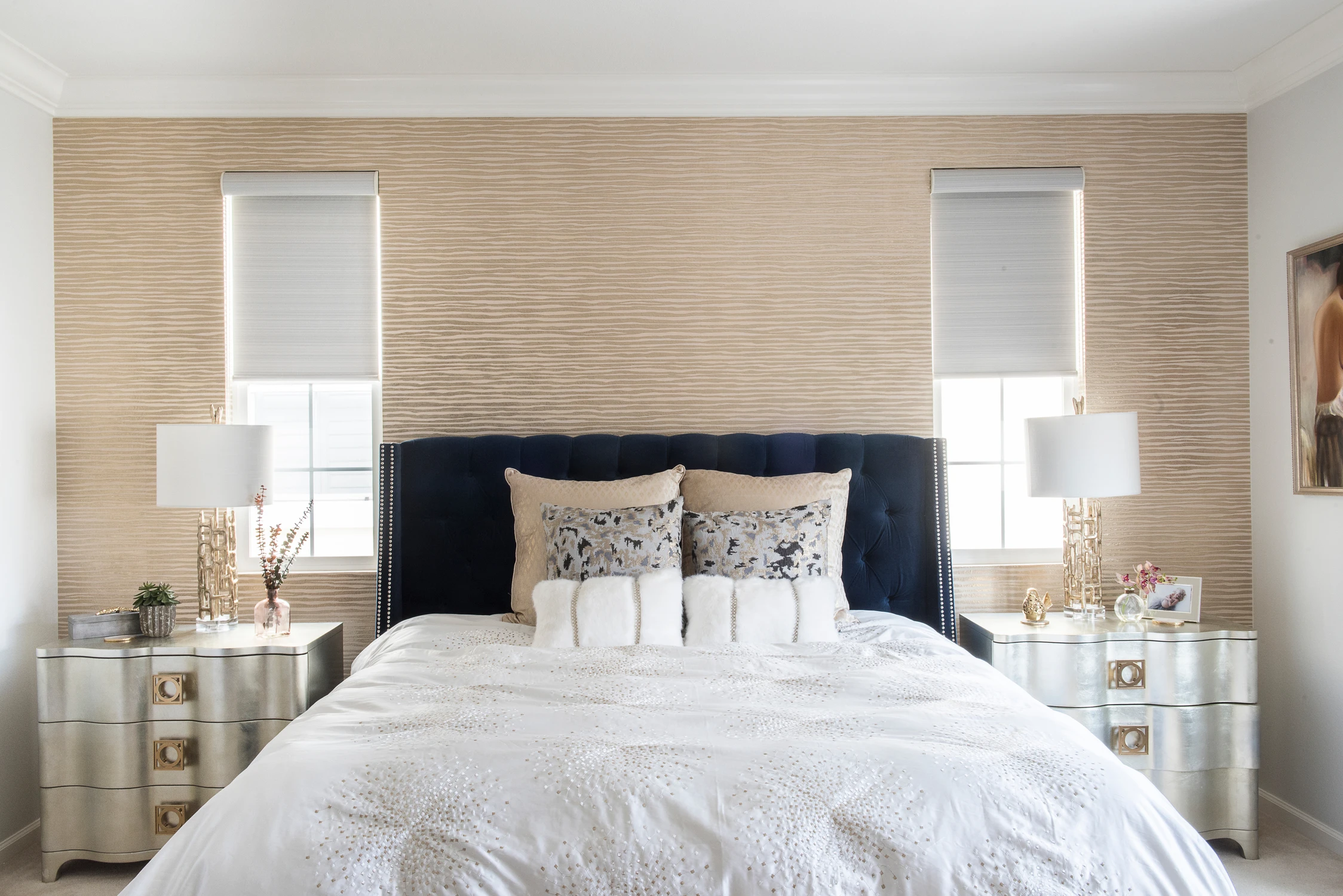 Bedroom with navy upholstered bed against a woven beige feature wall