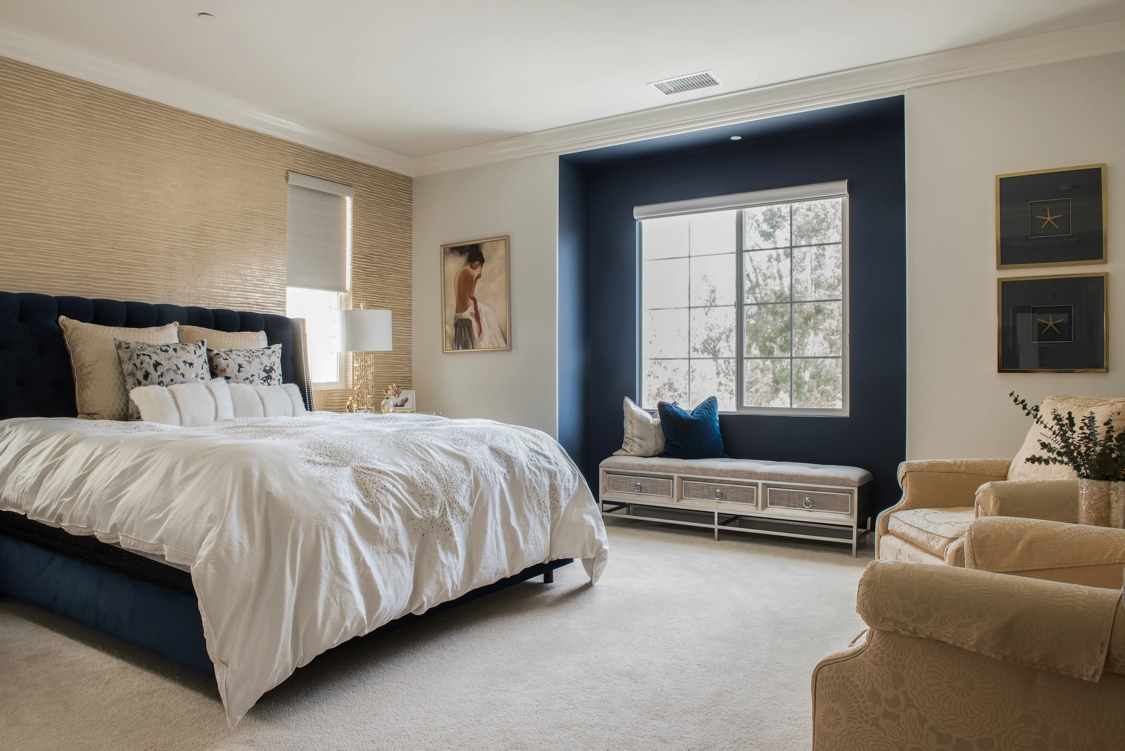 Bedroom with navy bed, dark window trim, and pale seating area
