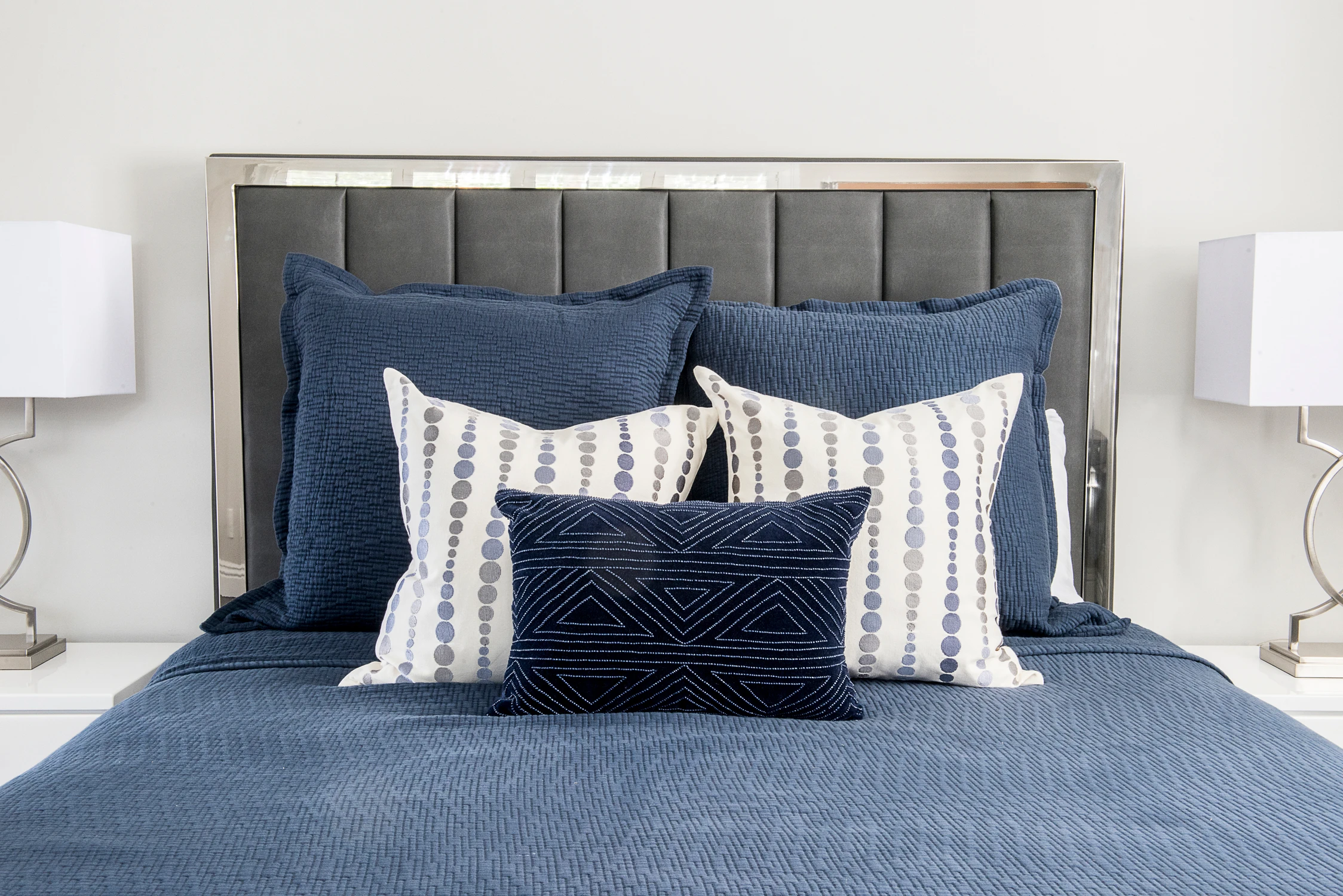 Bedroom with navy upholstered headboard and layered pillows