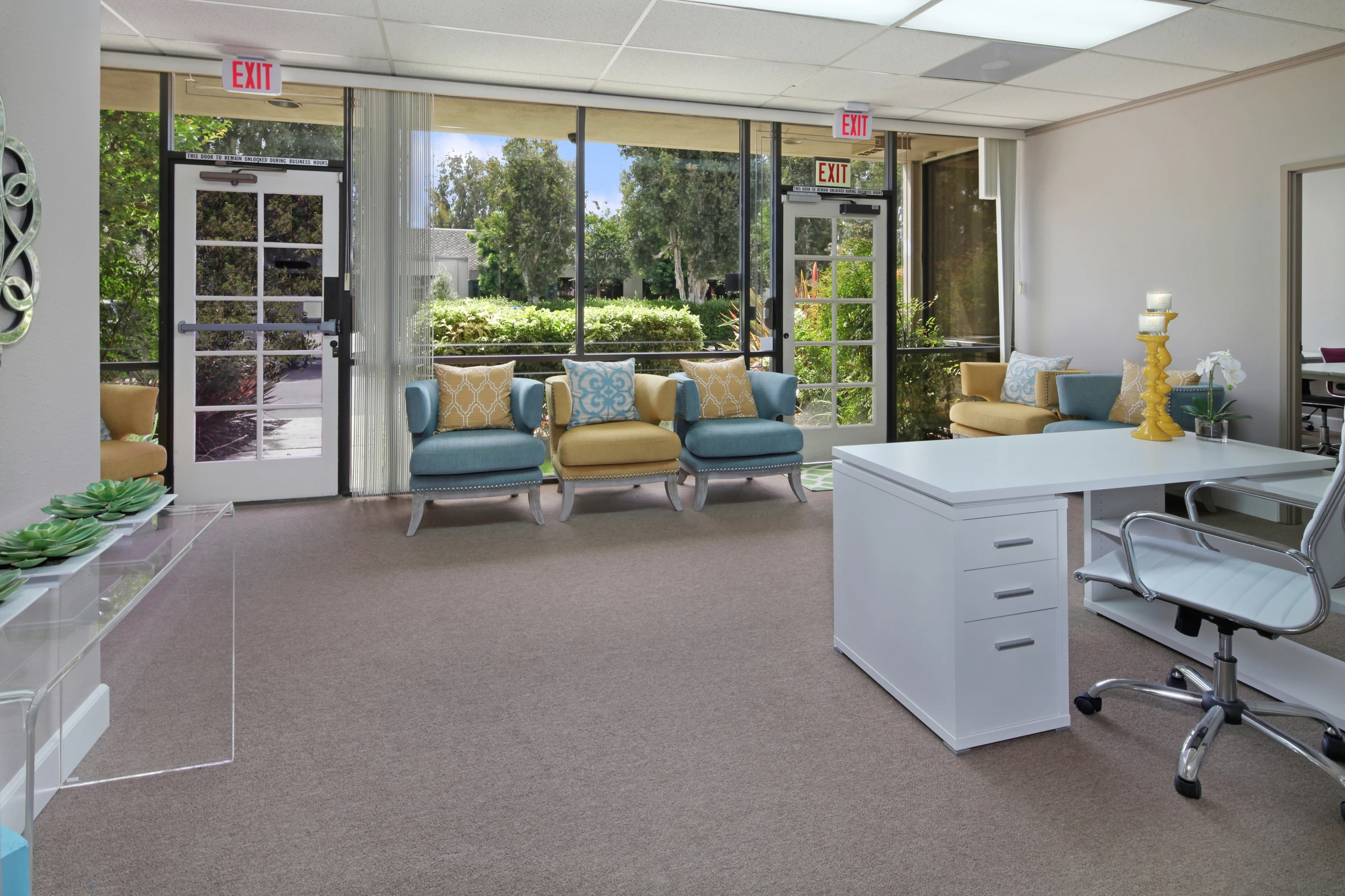 Reception desk facing window seating and a glass entry door