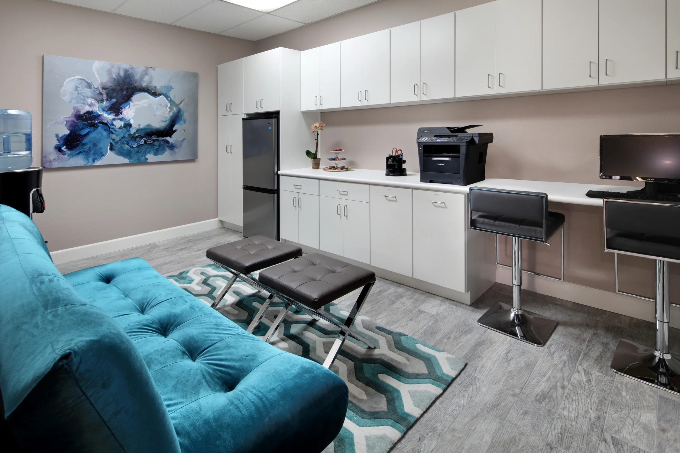 Staff break room with white cabinetry, coffee station, and turquoise sofa
