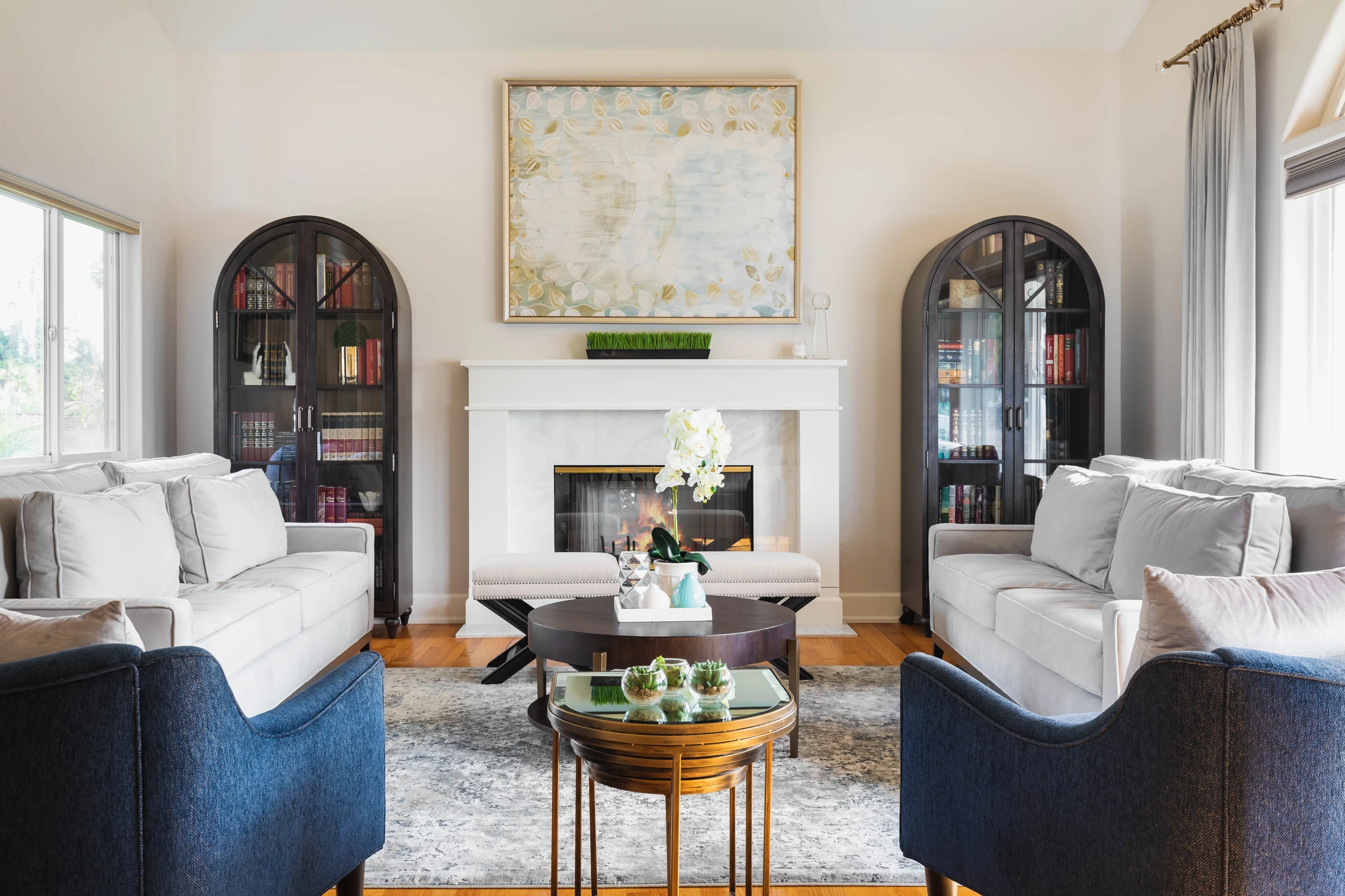 Bright living room with white sofas, blue chairs, and fireplace