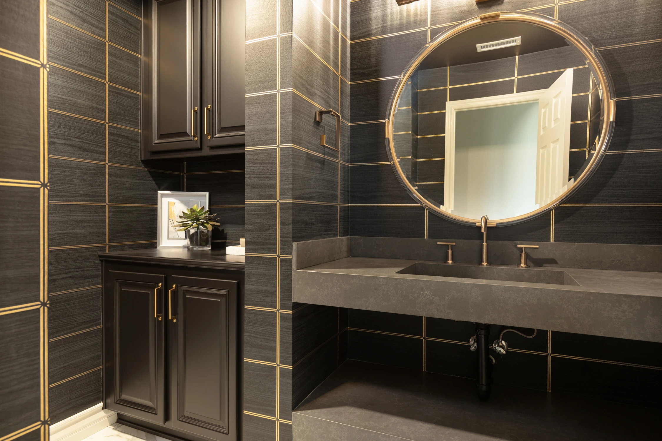 Powder room corner with dark tile, black cabinetry, and round mirror