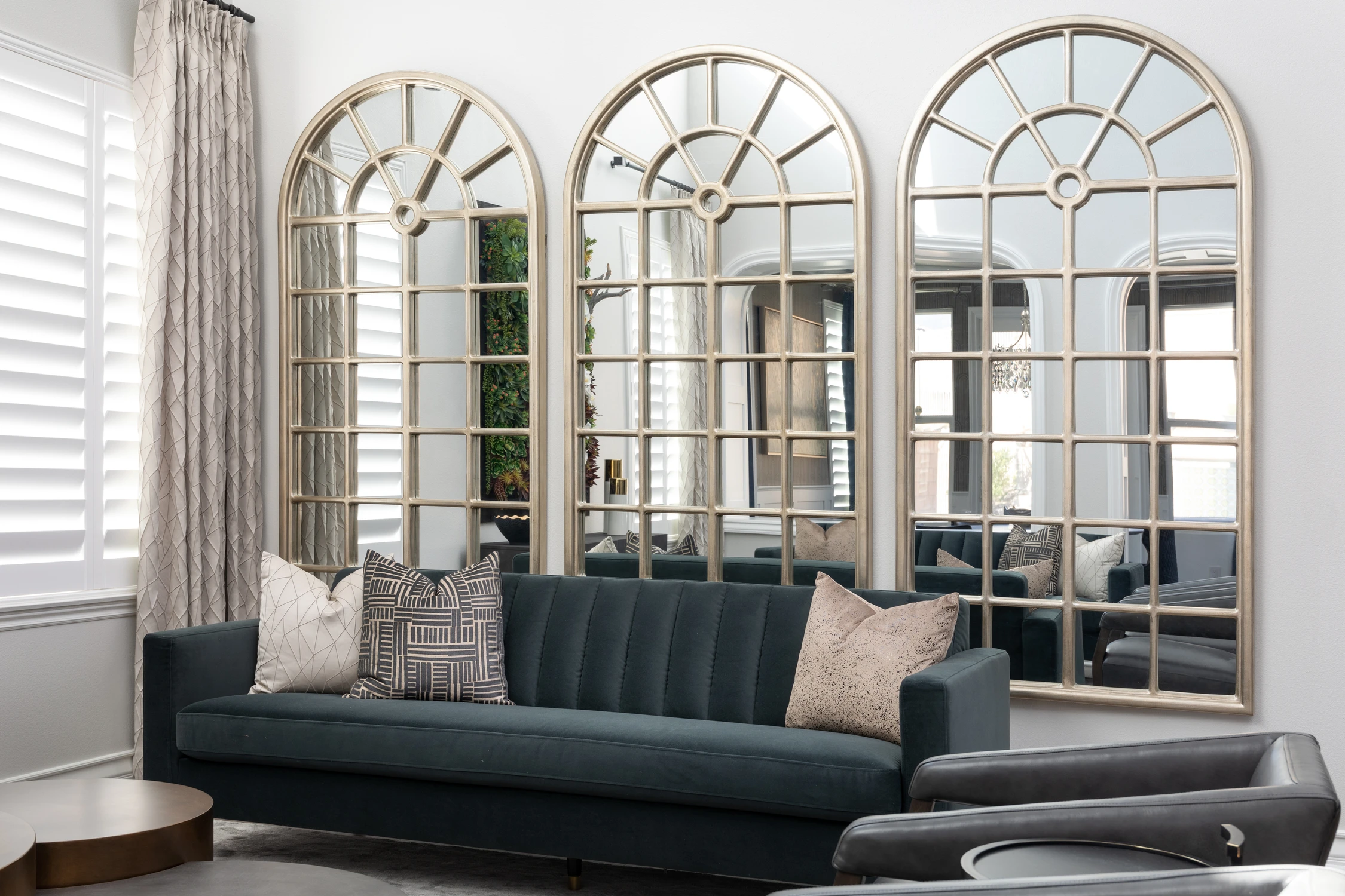 Teal living room sofa reflected in three arched mirrors