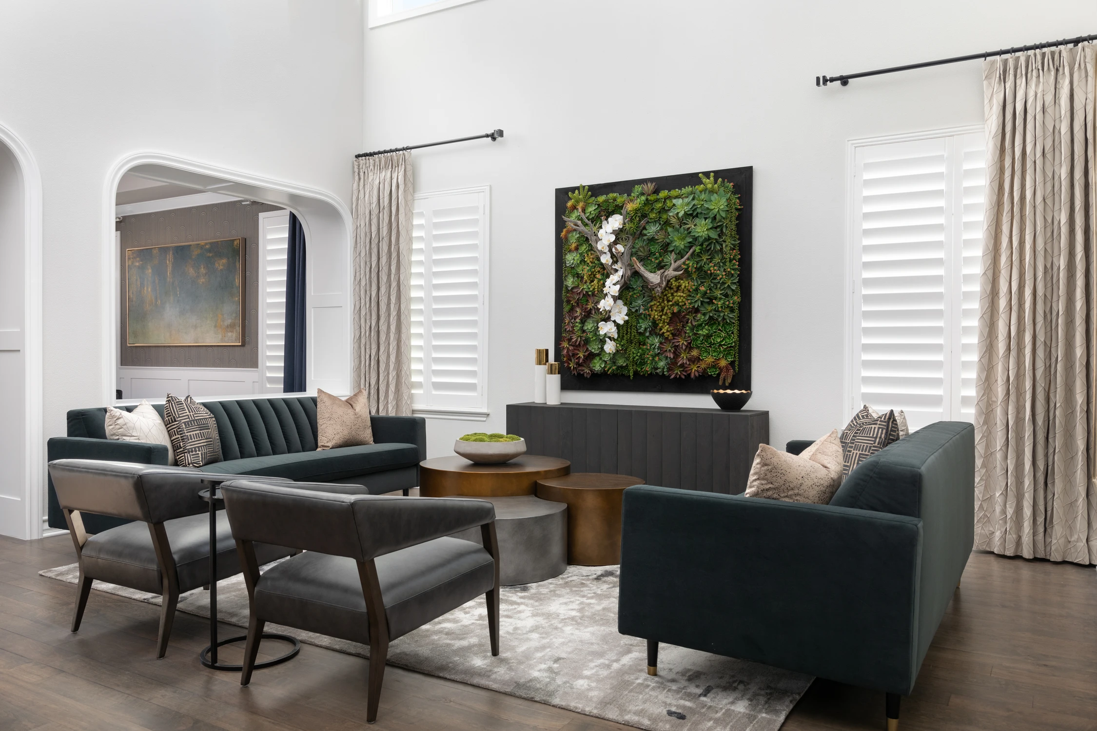 Living room with teal seating, arched doorway, and framed plant installation