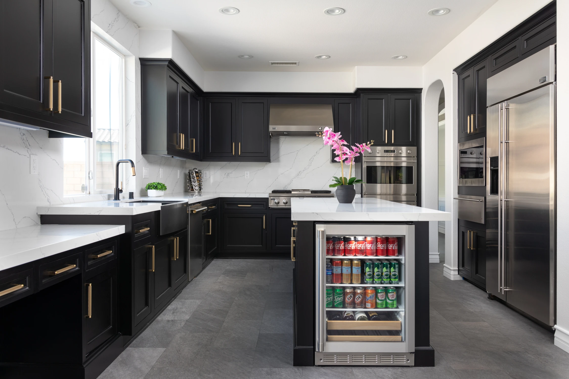 Black kitchen cabinetry with white stone counters and beverage drawer