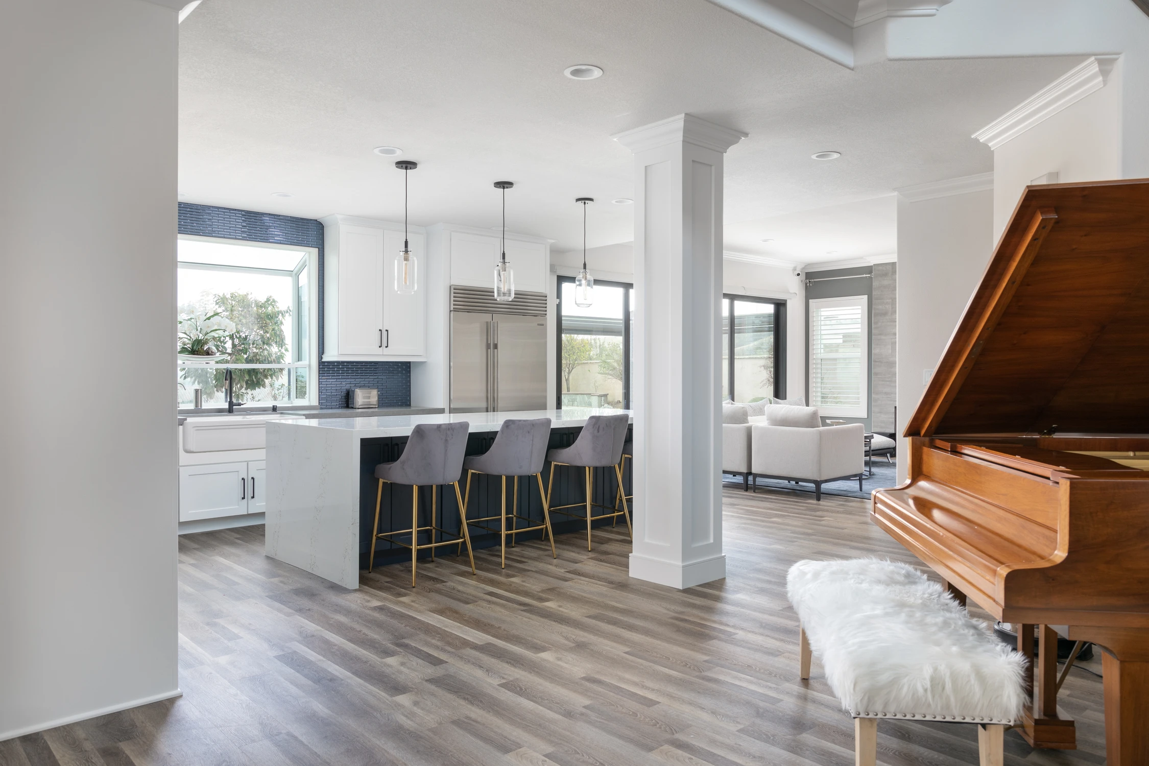 Open white kitchen with navy island and piano