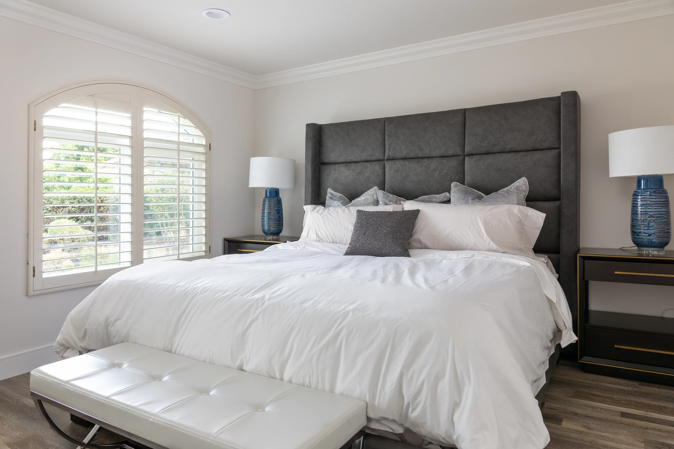 Bedroom with a charcoal paneled headboard and blue ceramic lamps