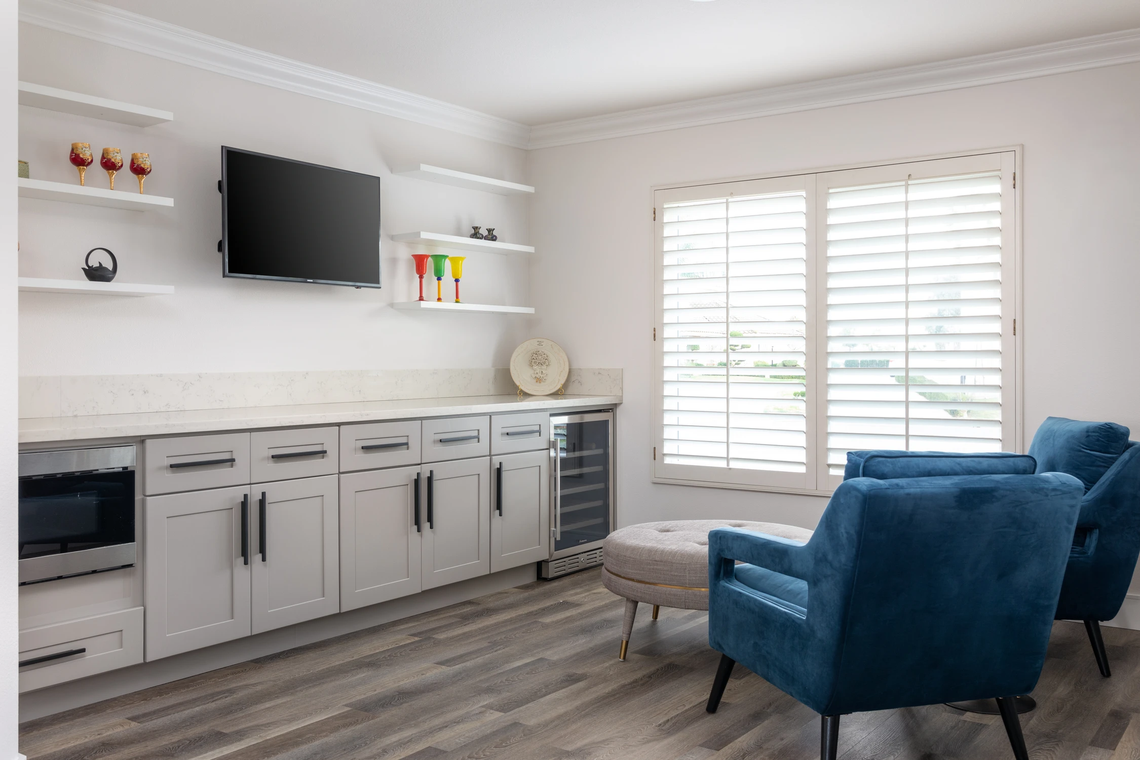 Media room with blue armchairs, gray cabinets, and wall-mounted television