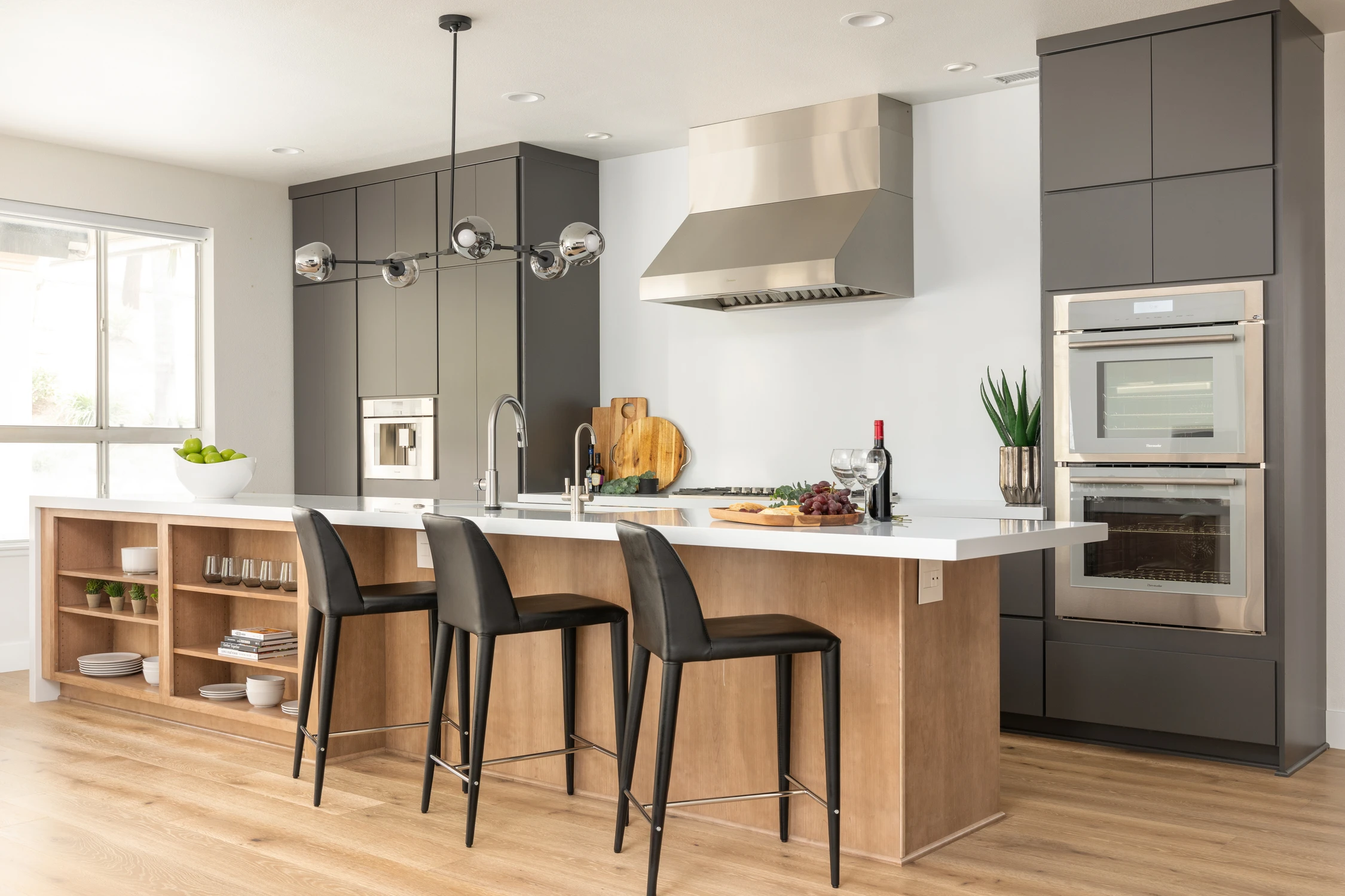 Kitchen with dark cabinets, wood island, and black bar stools