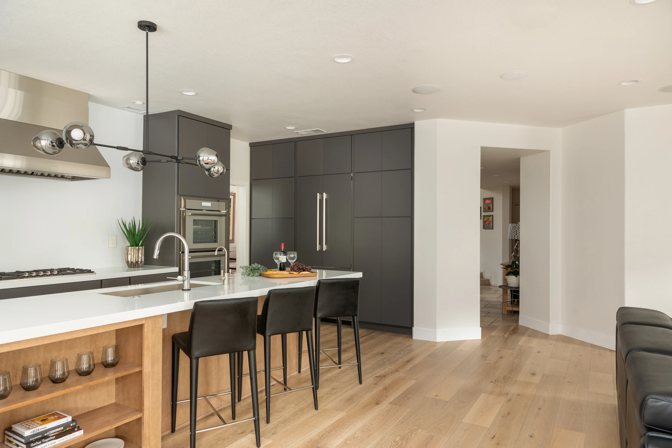 Kitchen island viewed beneath sculptural black globe pendant lights
